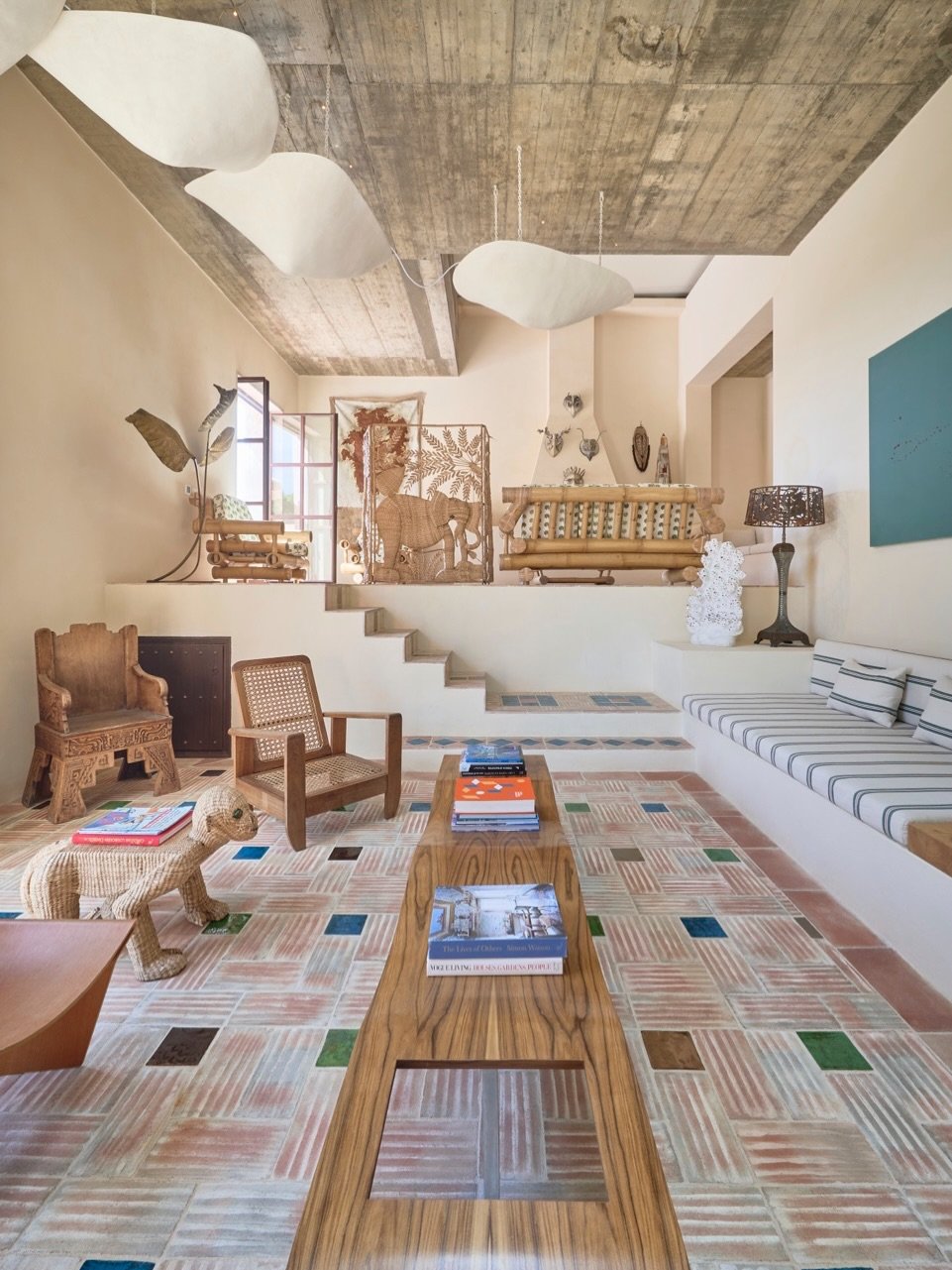 Living room with eclectic decor, patterned tile floor, wooden furniture, bamboo couch, and wall art.