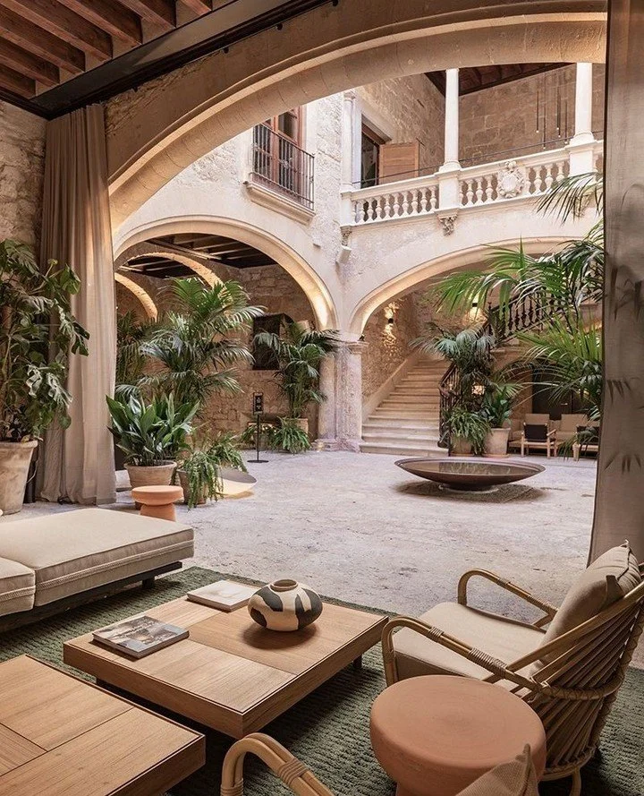 Luxurious indoor courtyard with stone architecture, plants, and elegant furniture.