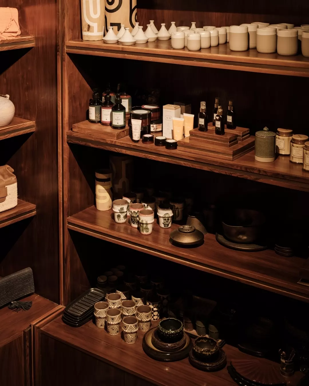 Wooden shelves displaying various ceramic and glass jars, cups, and bottles, with towels and decorative items.
