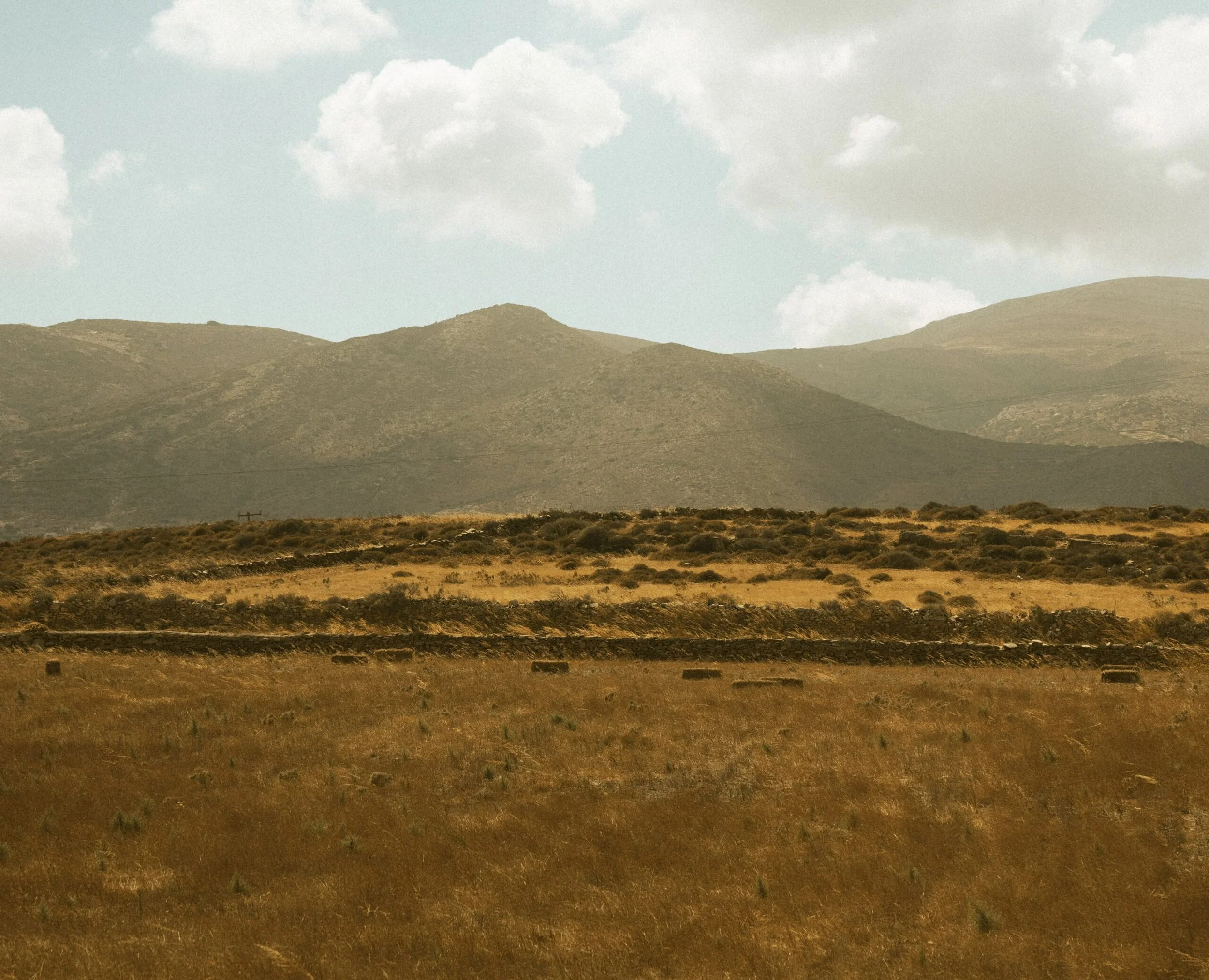 A landscape with rolling hills under a cloudy sky.