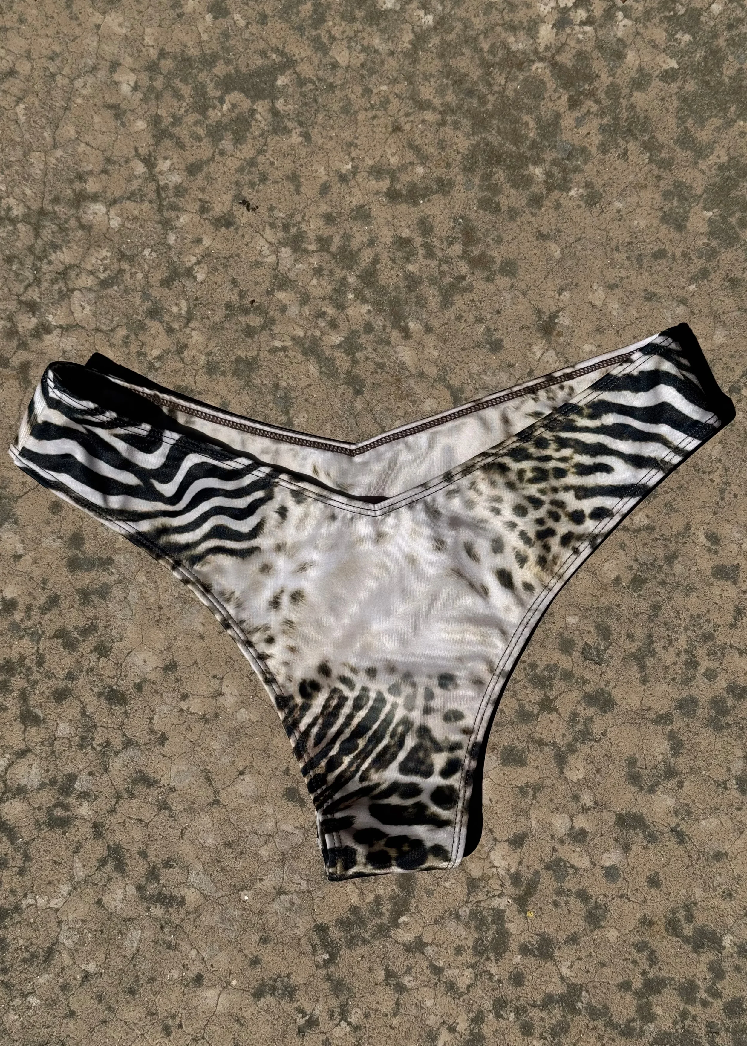 A black and white animal print clothing item, likely a pair of shorts or underwear, on a cracked concrete surface.