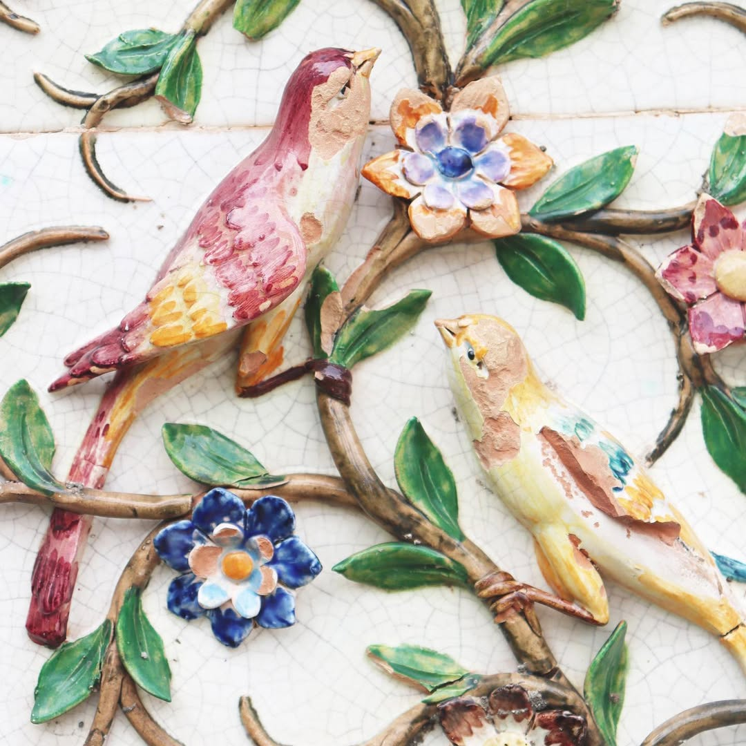 Colorful ceramic artwork depicting birds, flowers, and leaves with a cracked glaze background.