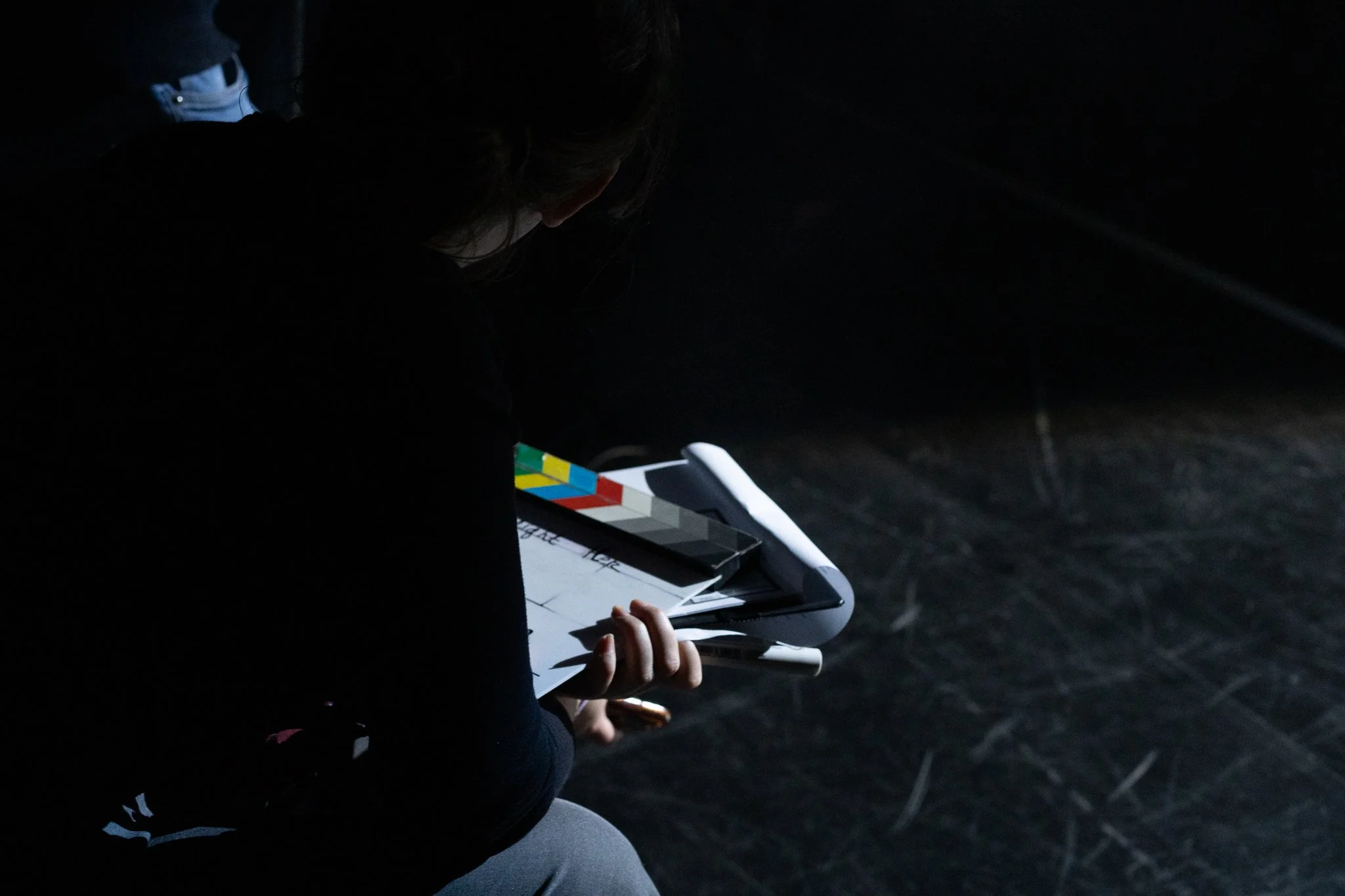 Une personne assise, utilisant une tablette dans un environnement sombre avec peu d'éclairage.