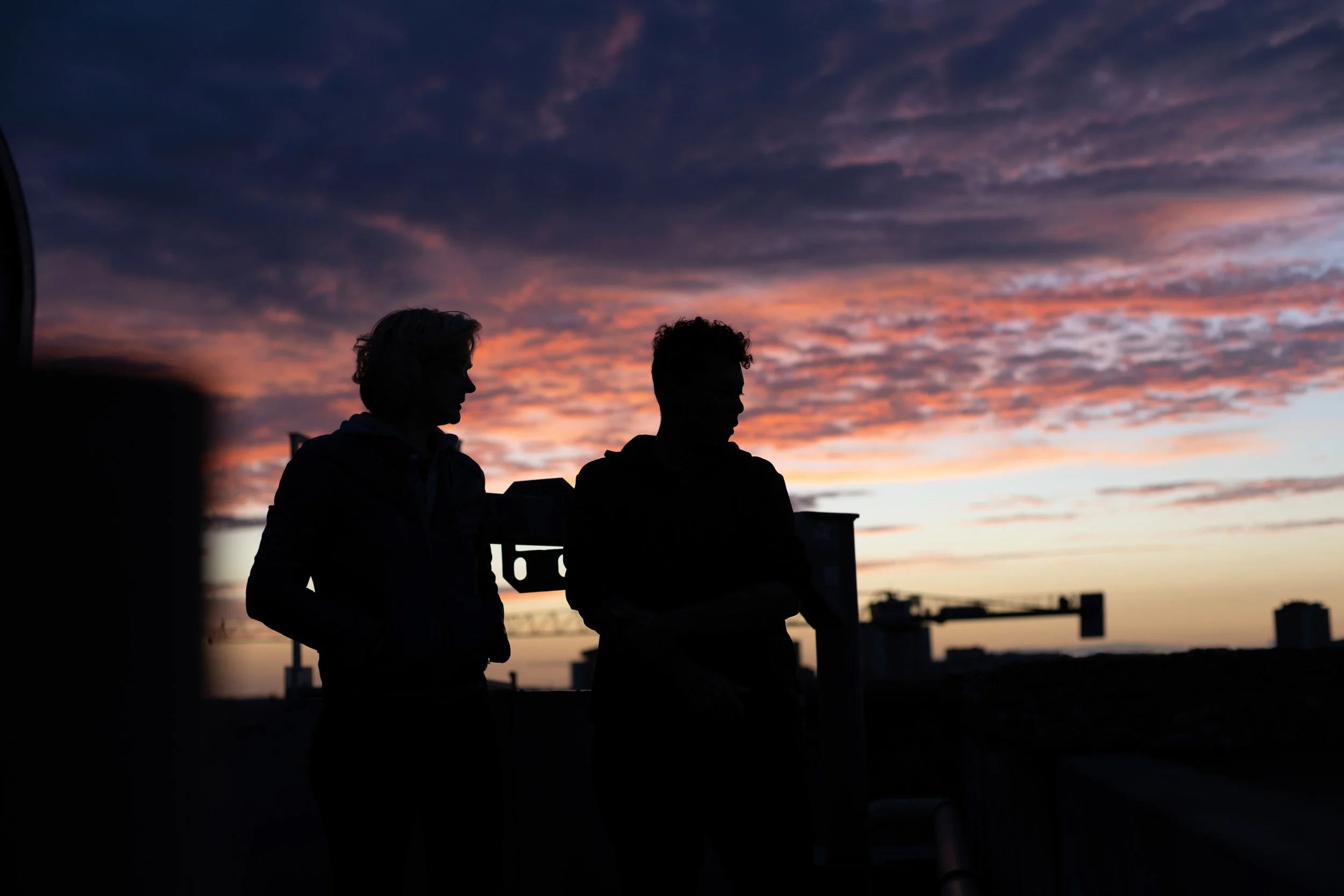 Silhouettes de deux personnes discutant à l'extérieur lors d'un coucher de soleil avec un ciel coloré en arrière-plan.
