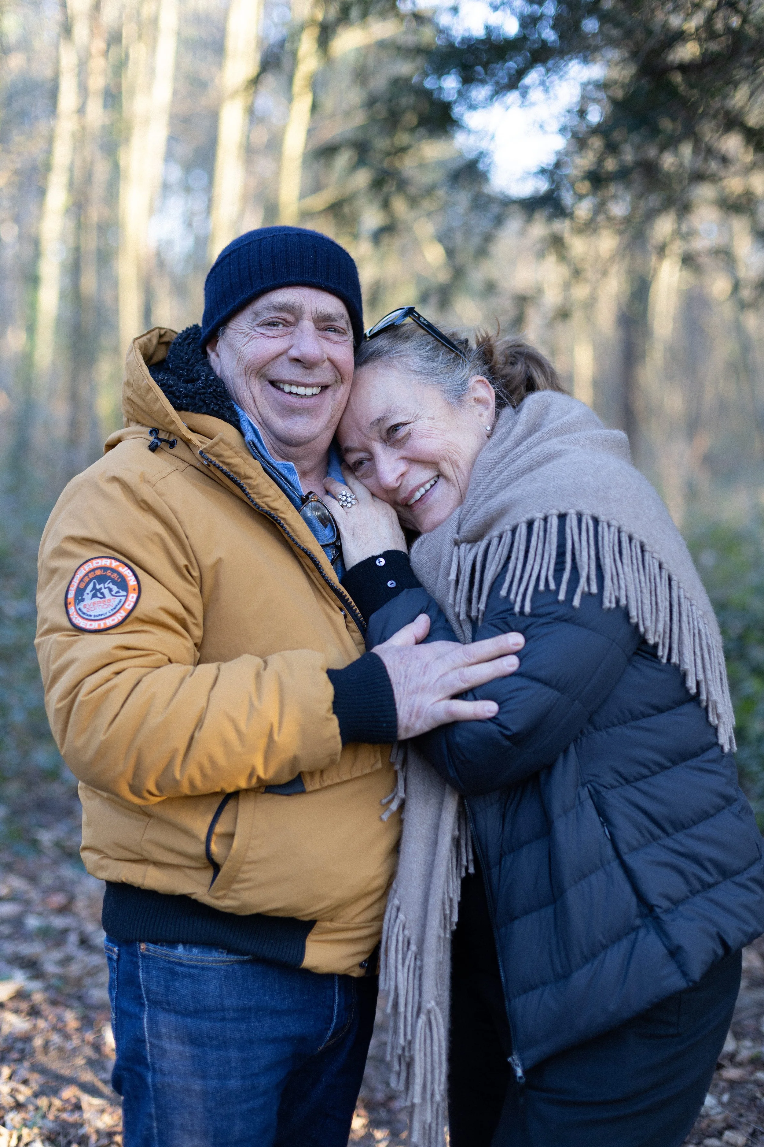 Un homme et une femme qui s'étreignent et sourient dans une forêt.