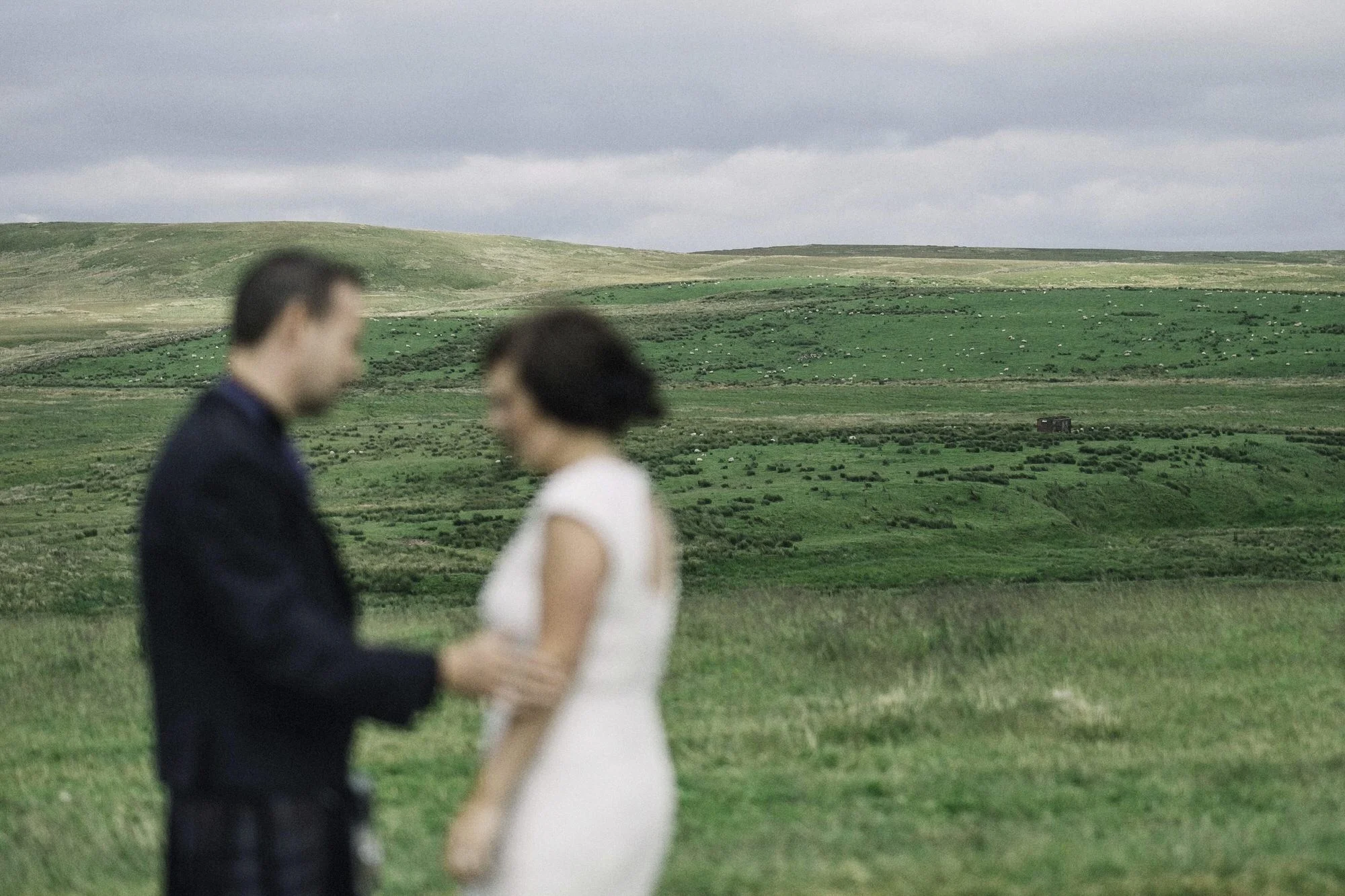 Bride & groom stand in a field