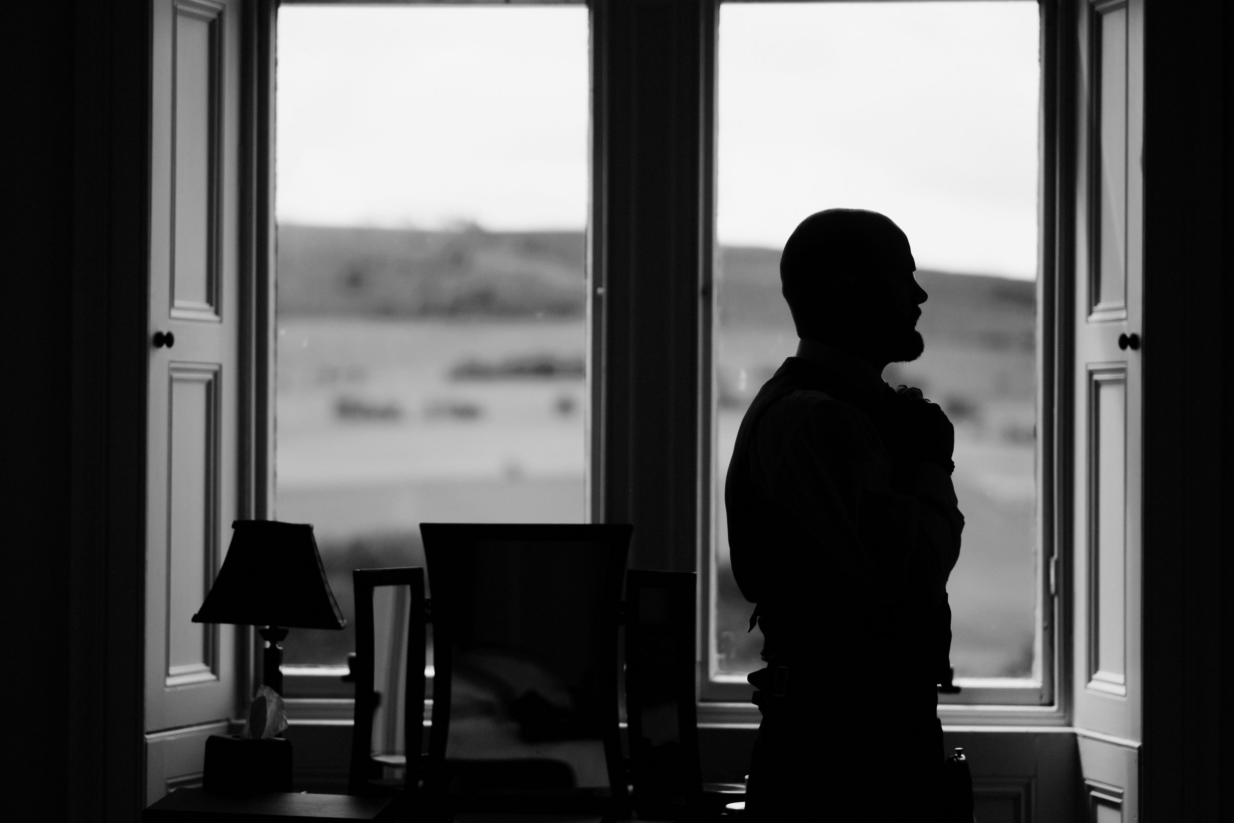 Groom stands by window