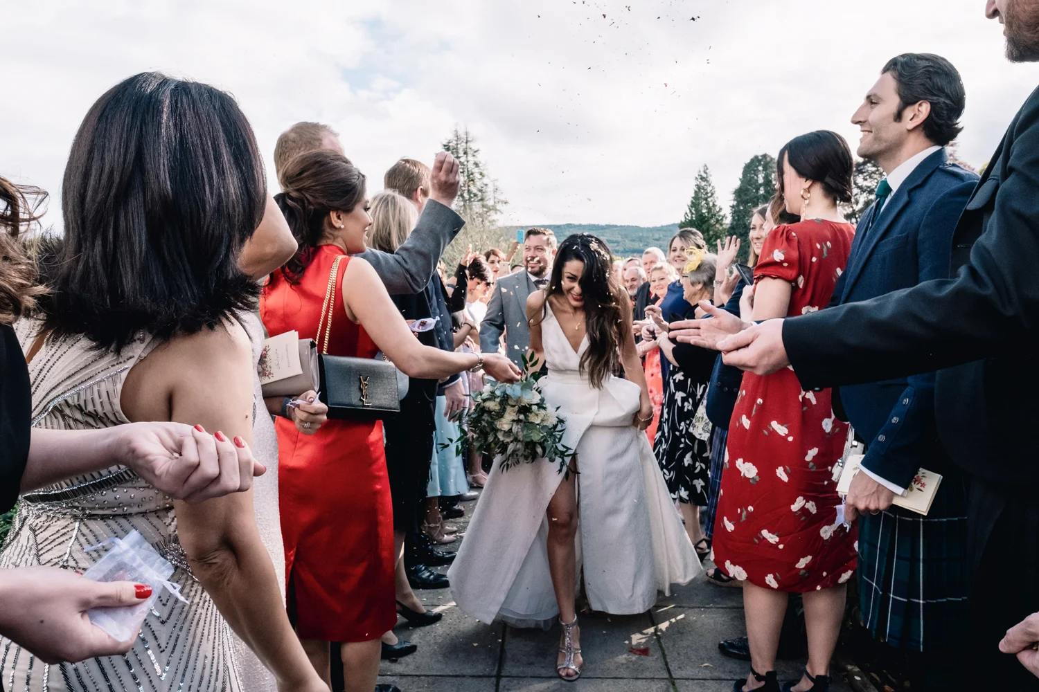  Bride + groom laugh as confetti is thrown at them. 