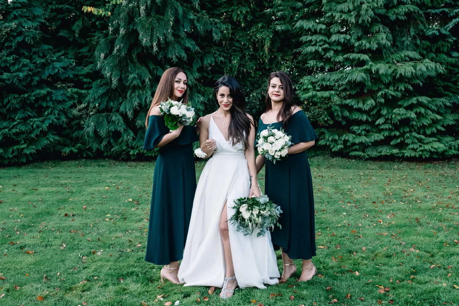  Bride looks to camera smiling with a bridesmaid on either side. 
