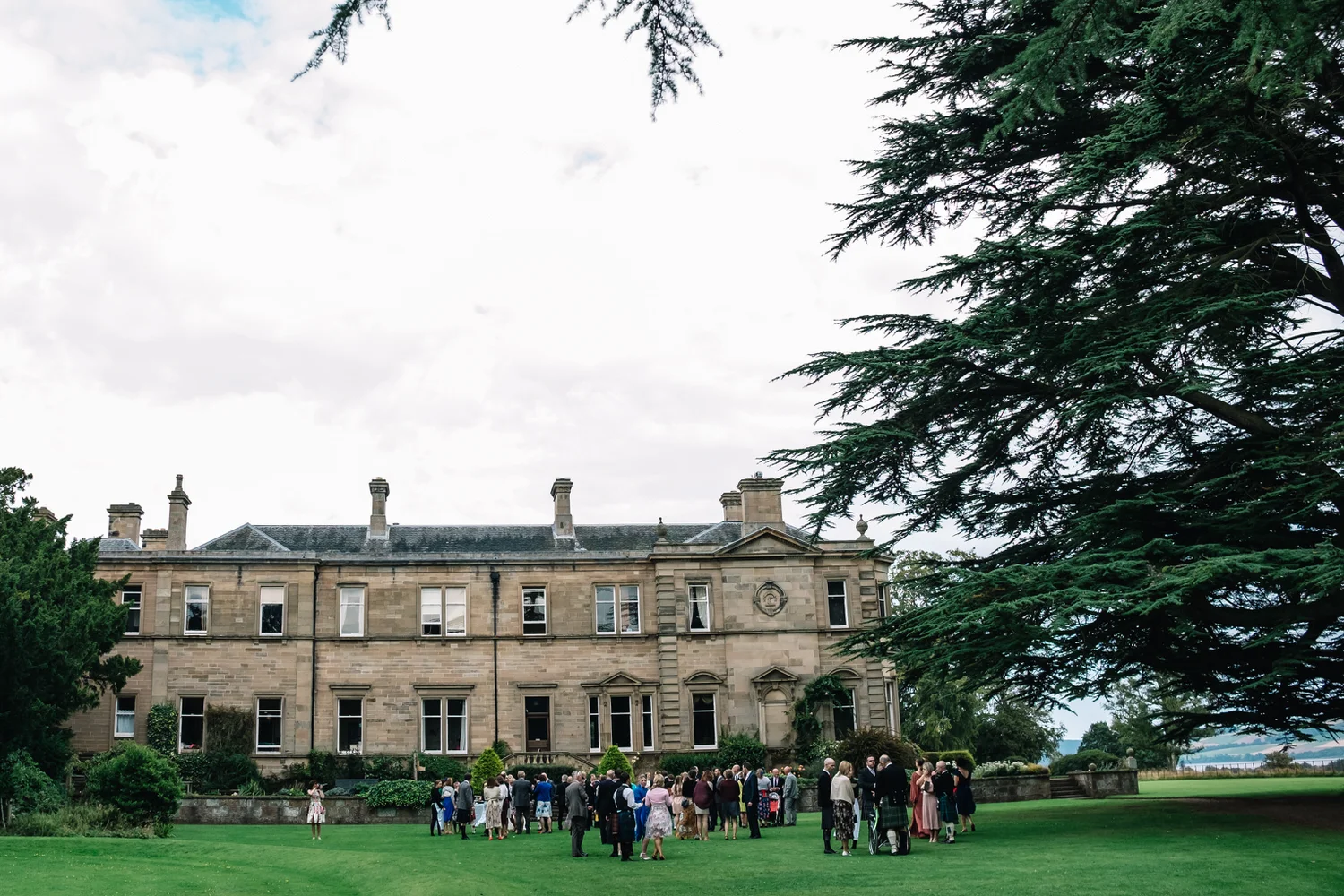 Guests enjoy the drinks reception on from the wedding outdoor, summer cereony. 