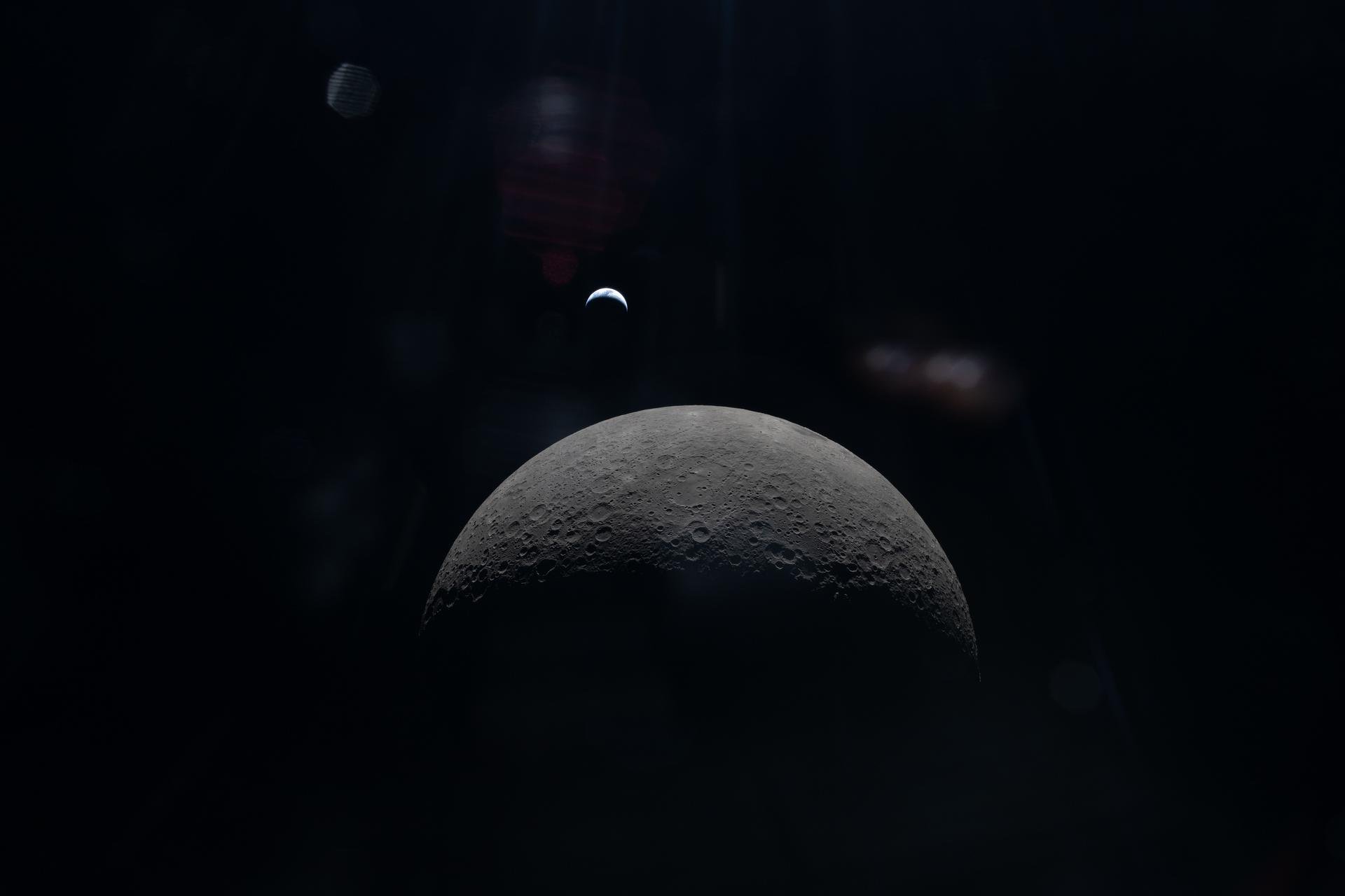 View of the moon's surface with the Earth visible in space behind it.