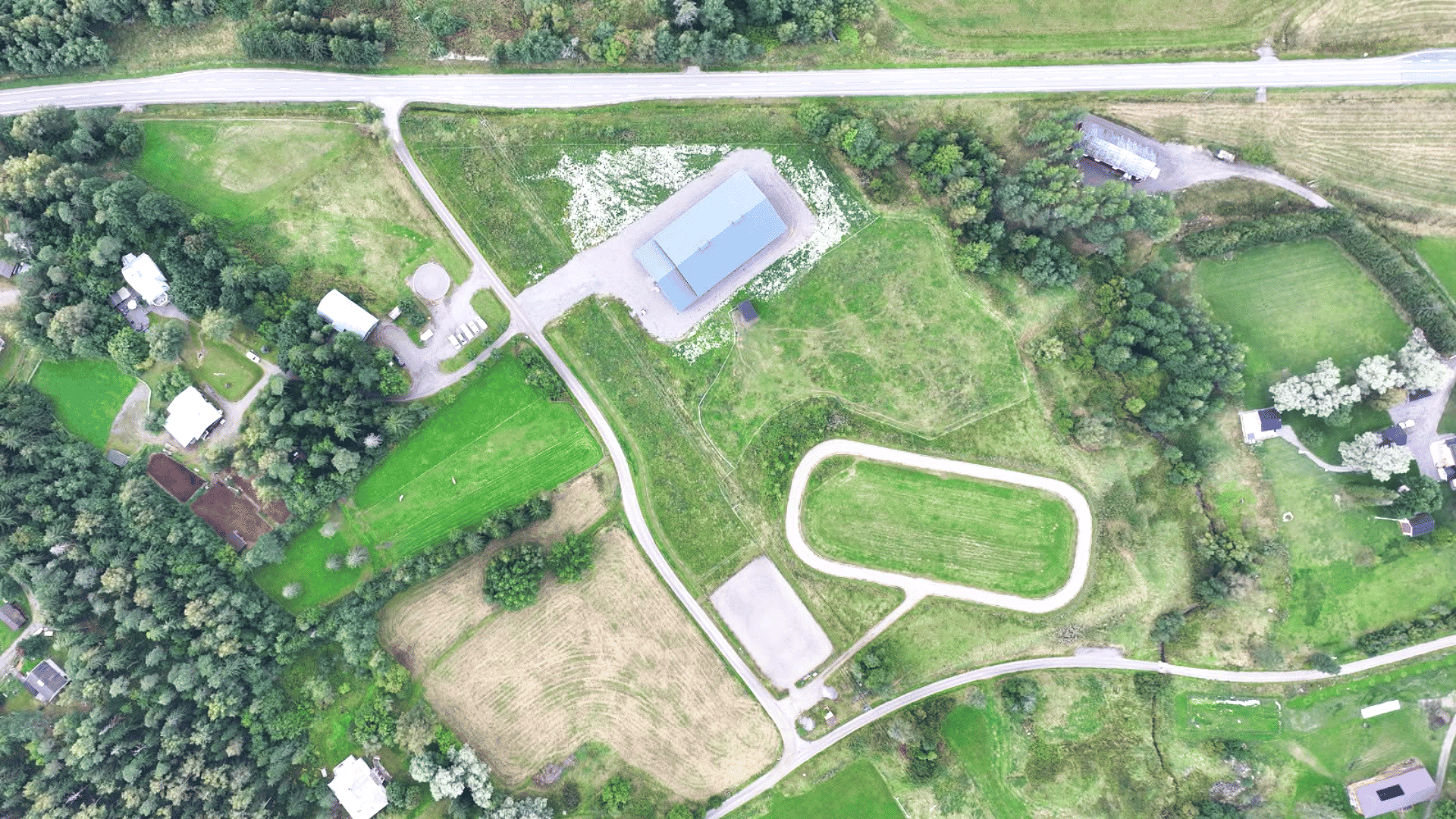 Satoa ja tietä, rakennuksia ja puita, maisema drone-kuvassa.