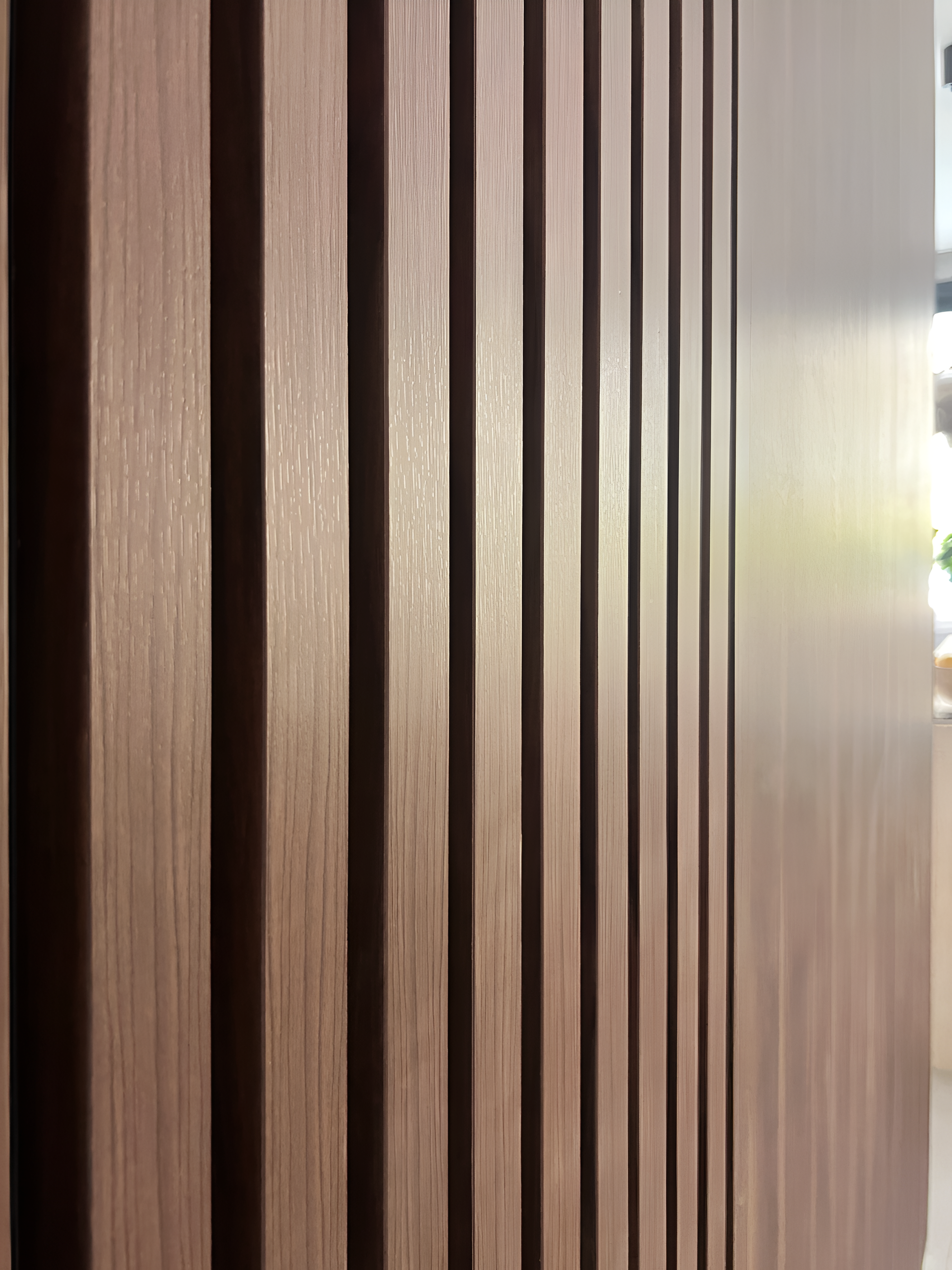 Close-up view of vertical wooden slats on a wall or furniture, showing the texture and grain of the wood.