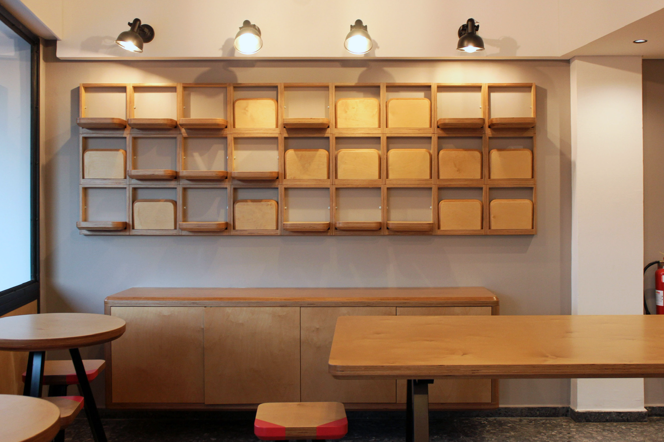 Wooden shelves and tables in a cafe or workspace with minimalist design and lighting.