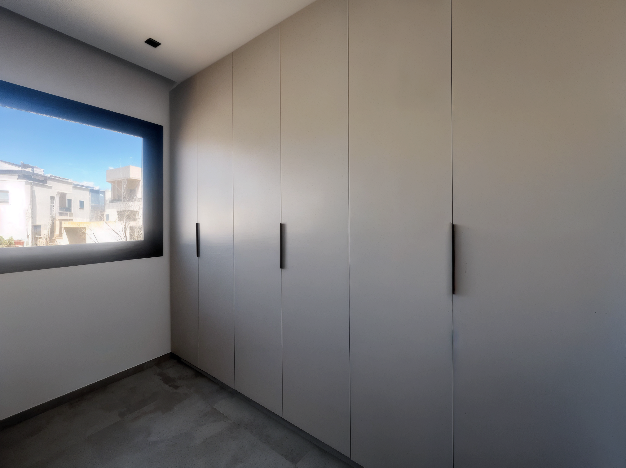Interior view of a room with a large window showing buildings outside. Inside, there is a tall white cabinet with black handles, and a gray tile floor.