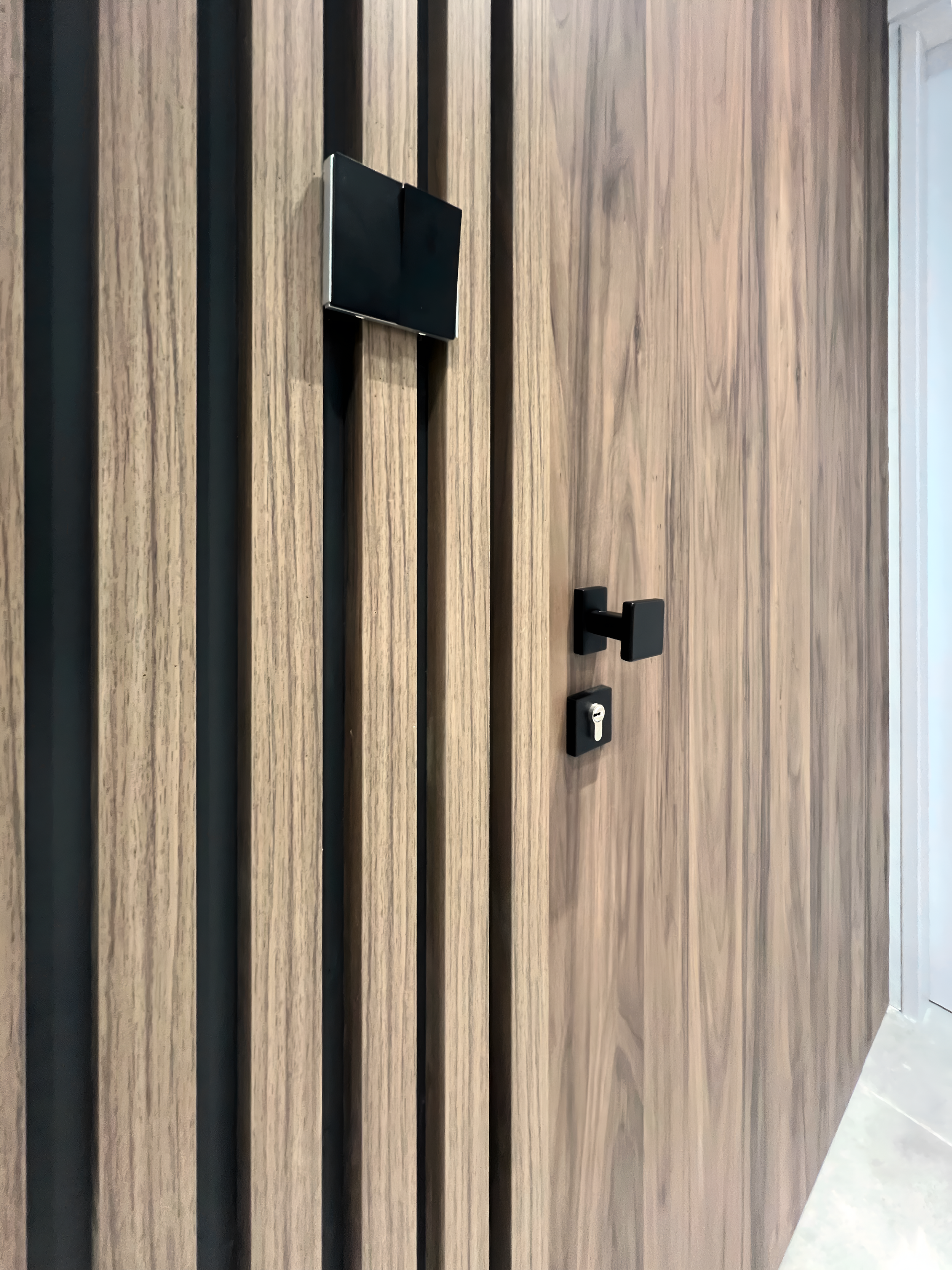 A wooden slat wall with black horizontal inserts, a lockable door handle, and a small lock.