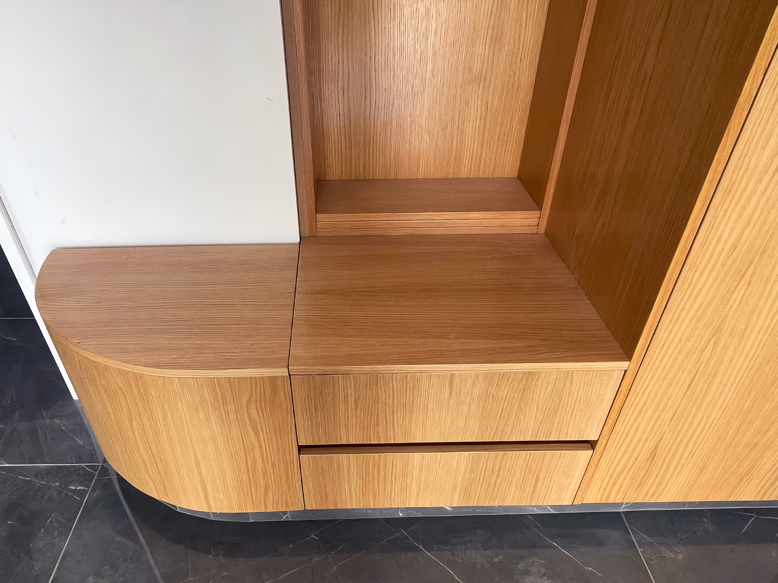 Wooden cabinets with curved edges and a dark marble floor.
