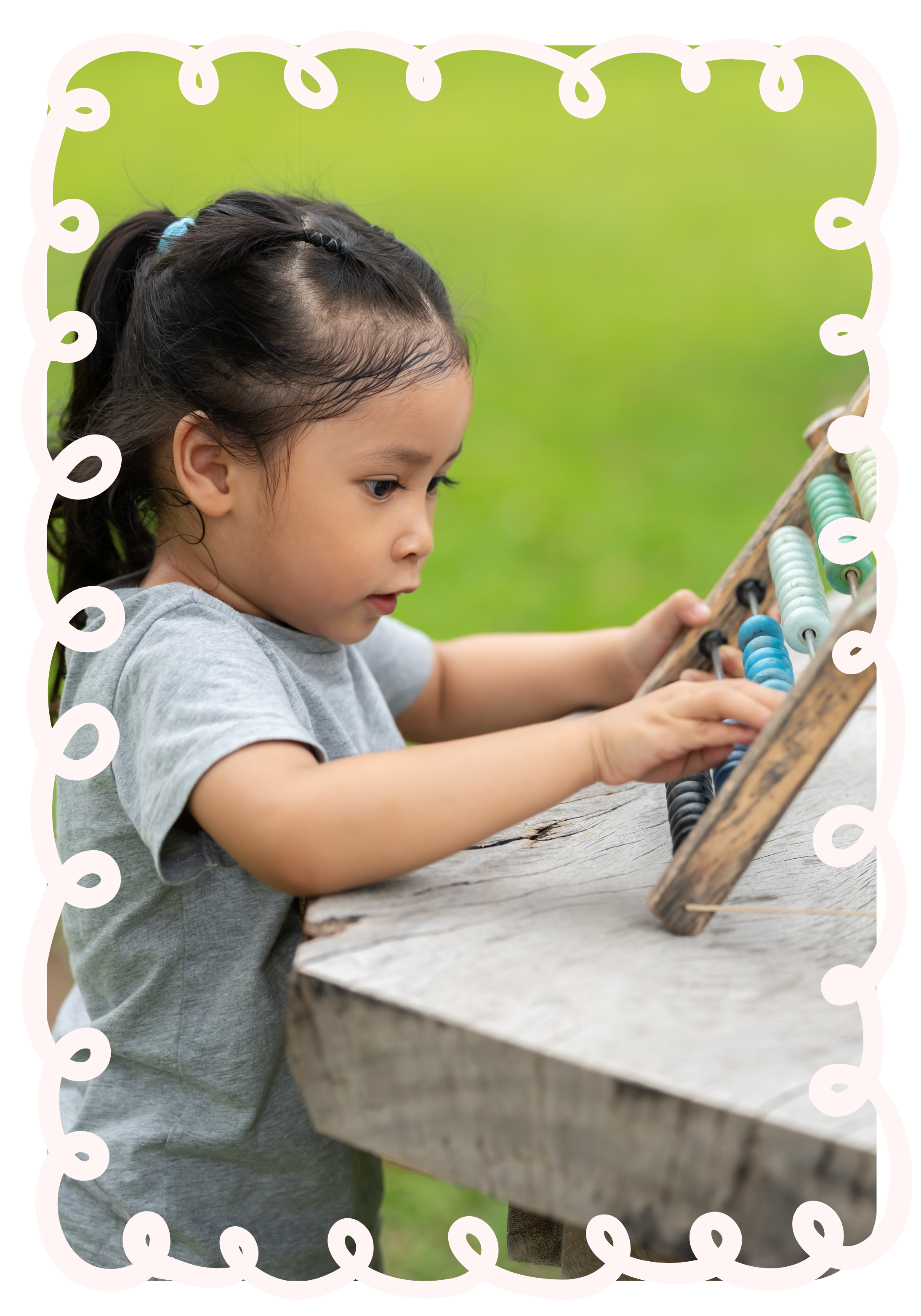 A young girl with dark hair in a ponytail playing an abacus outdoors on a wooden table, with green grass in the background to represent Strong Roots OT where we provide occupational therapy services for pediatrics and maternal health in South NJ.