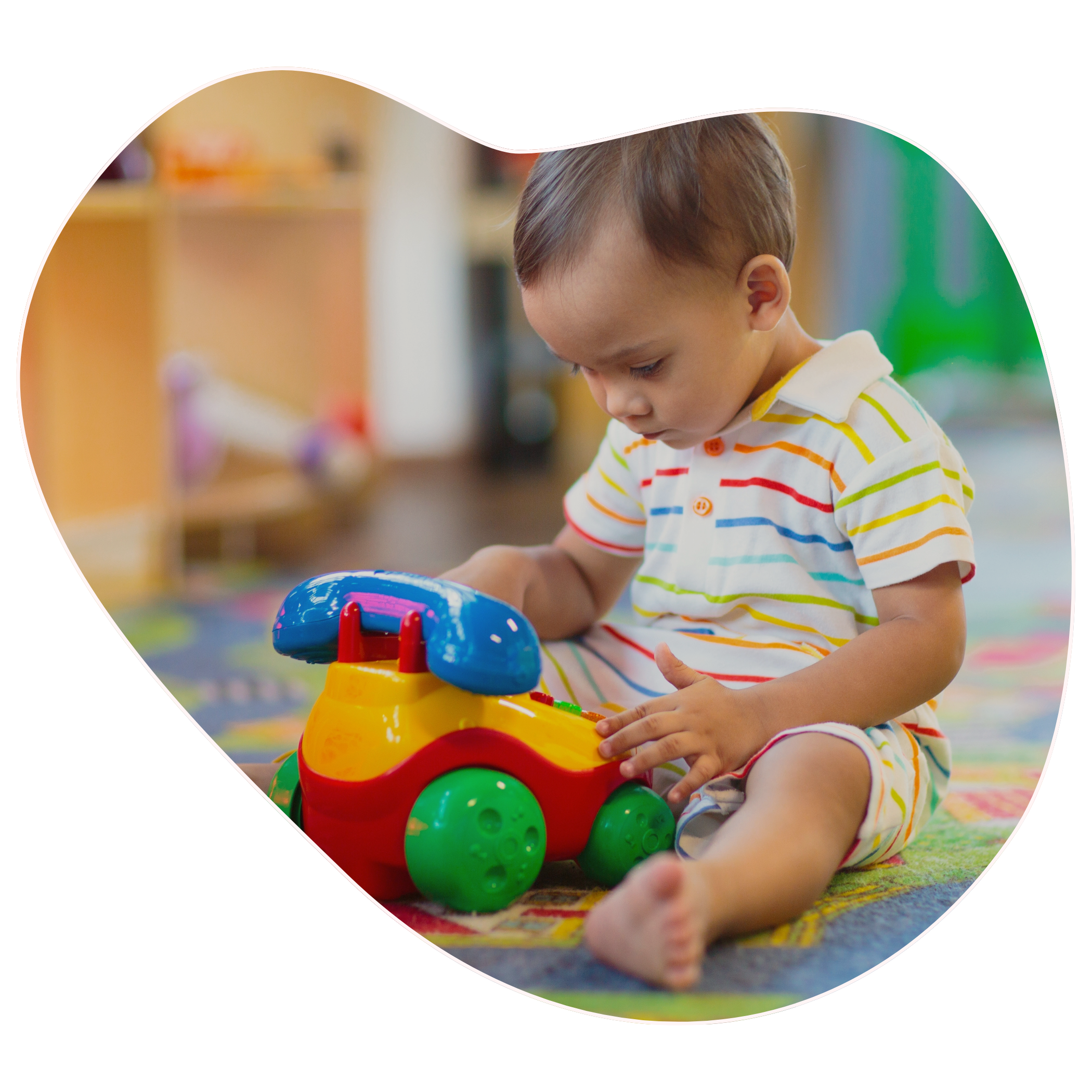 A young boy sitting on a colorful rug playing with a toy castle with multicolored plastic balls inside to represent fine motor skills in young children and toddlers at Strong Roots OT in south NJ & Philadelphia.