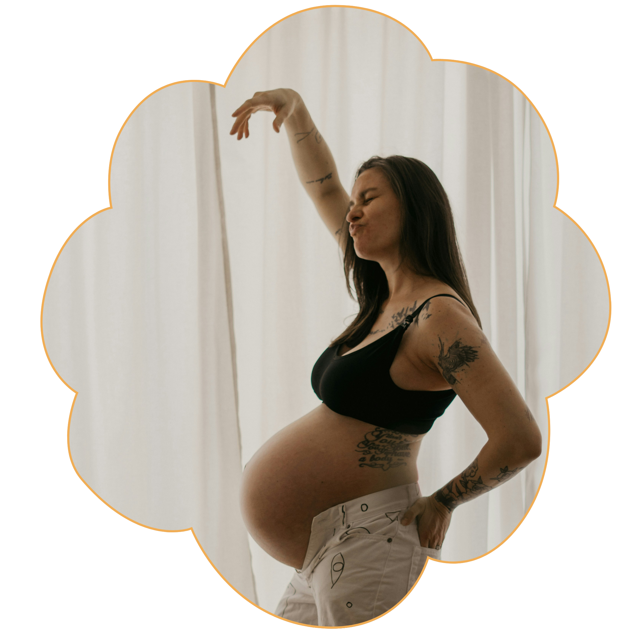 A pregnant woman with tattoos on her shoulder and arm, wearing a black bra and beige shorts dancing in front of a window to represent Strong Roots OT, an occupational therapy clinic in south New Jersey & Philadelphia.