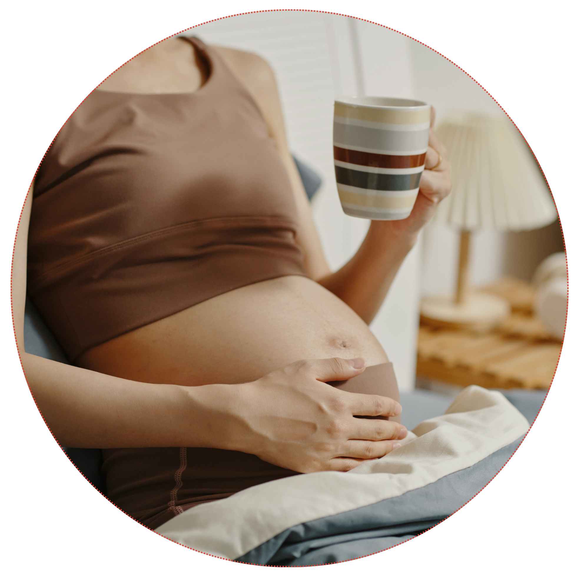 Pregnant bellow of a woman sitting on a couch holding a striped ceramic mug to represent the prenatal clients at Strong Roots OT in south NJ and Philadelphia where we provide maternal health and pediatric occupational therapy services.