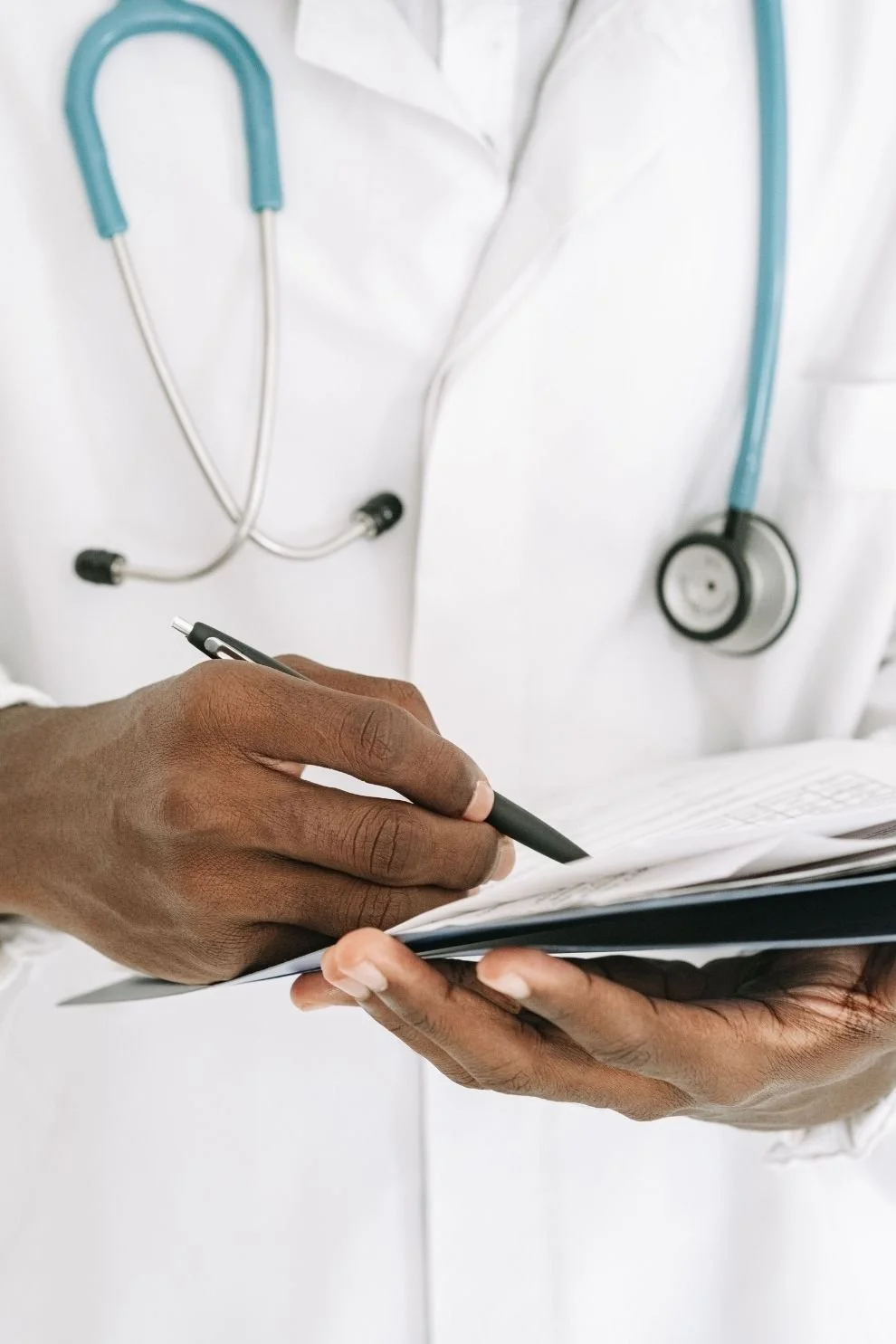 Close-up of a physician documenting notes on a patient chart, reflecting physician executive coaching and executive coaching for physicians focused on decision-making, leadership skills, and practice management.