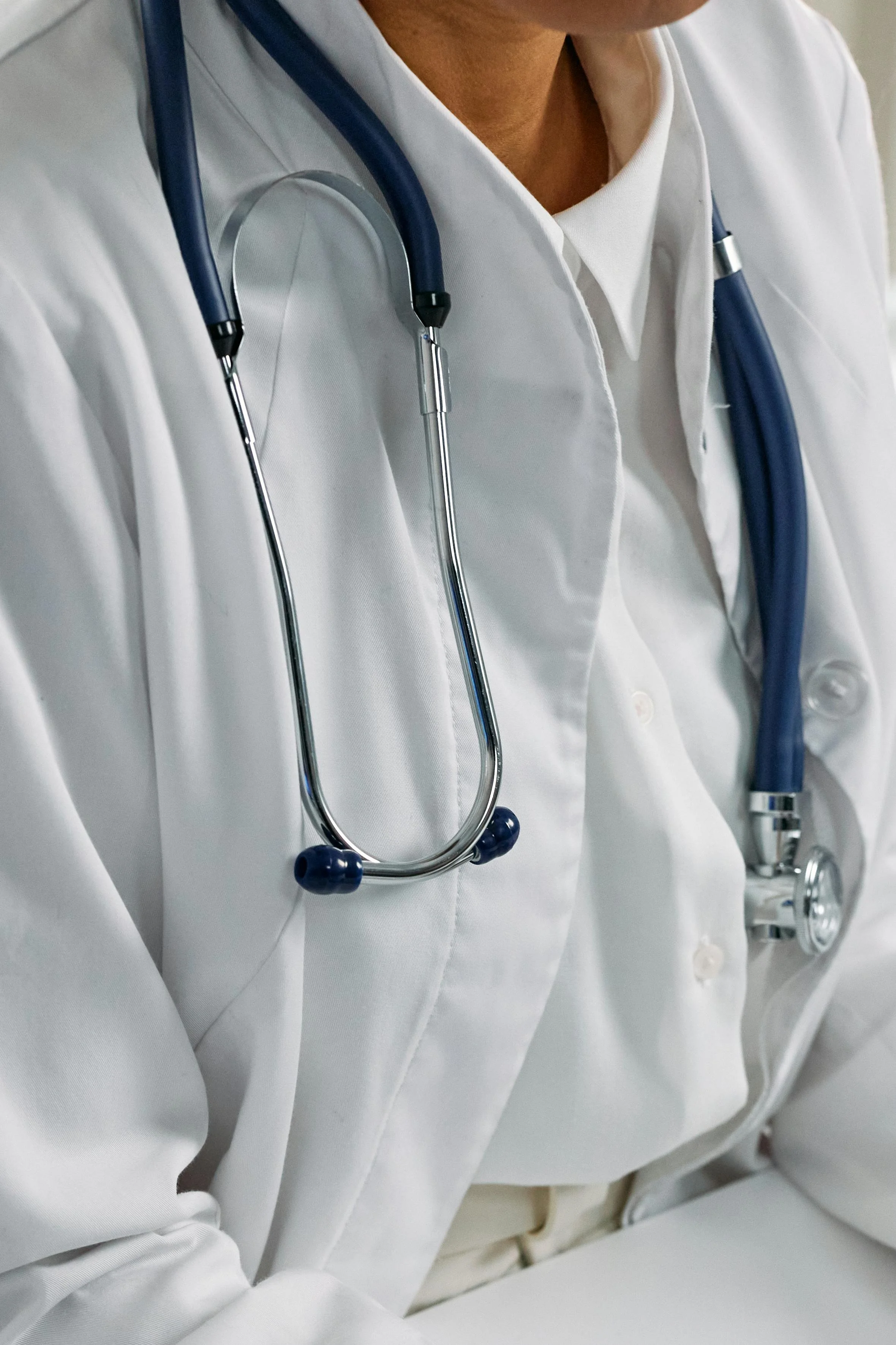 Close-up of a healthcare professional wearing a white medical coat and stethoscope, representing expertise shared through speaking engagements focused on leadership, patient care, and healthcare innovation.