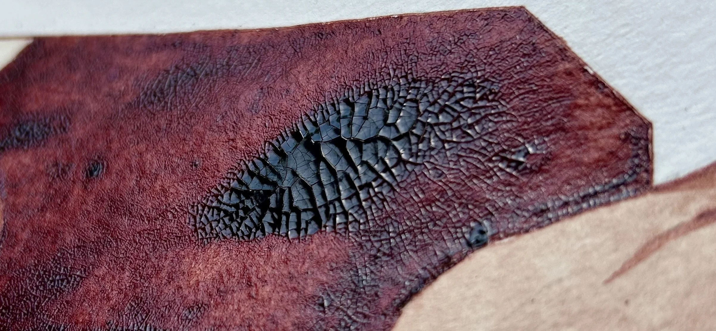 Close-up image of a red and black textured surface, possibly a burned or heat-damaged material with cracked black areas.