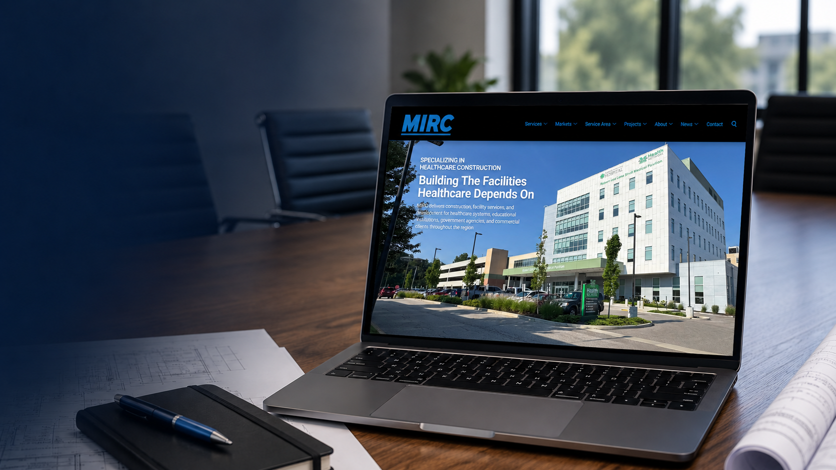 MIRC Construction healthcare project website displayed on a laptop with architectural plans and construction documents.