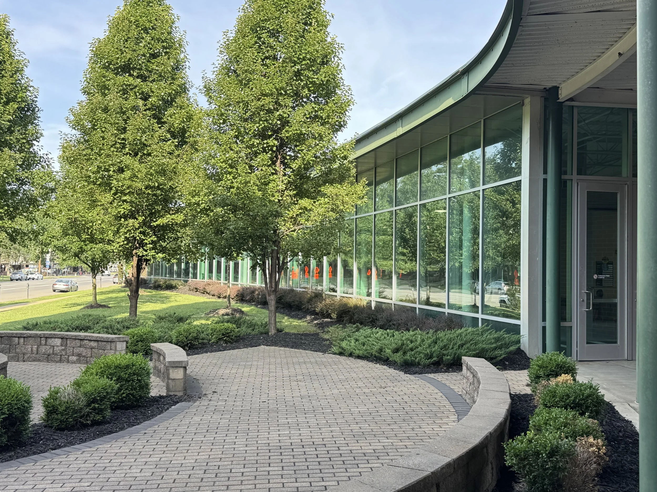 Landscaped courtyard and curved glass exterior of the Arthur Weisberg Family Applied Engineering Laboratories at Marshall University.