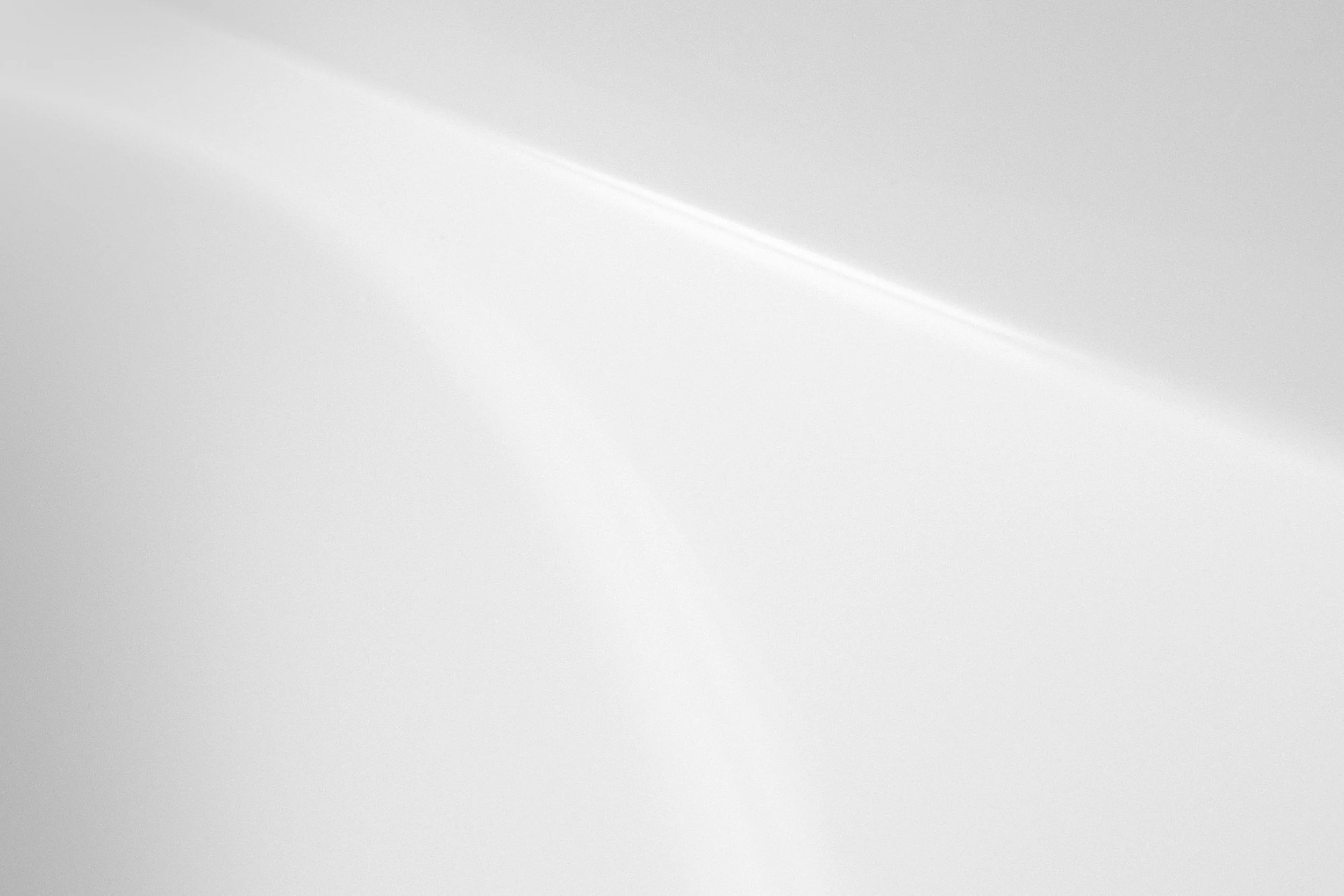 A plain white surface with a diagonal shadow or line running across it.