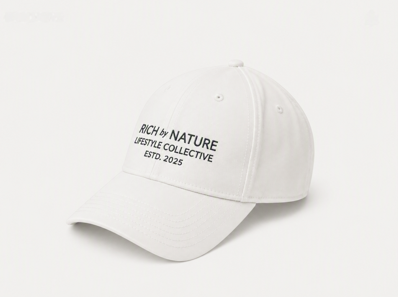En svart caps med tekst som sier RICH by NATURE LIFESTYLE COLLECTIVE ESTD. 2025