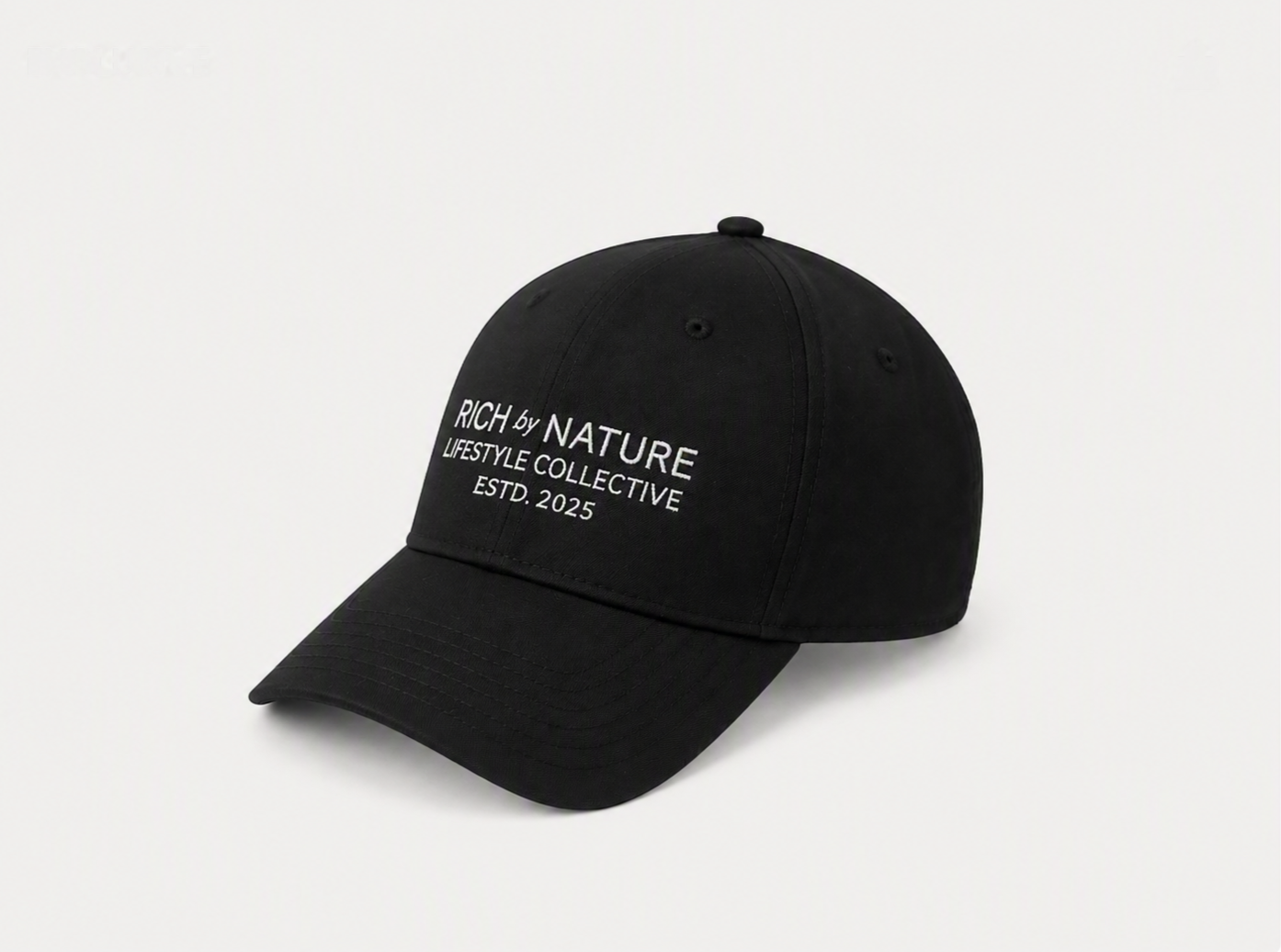 Svart caps med tekst som sier "RICH by NATURE LIFESTYLE COLLECTIVE ESTD. 2025".