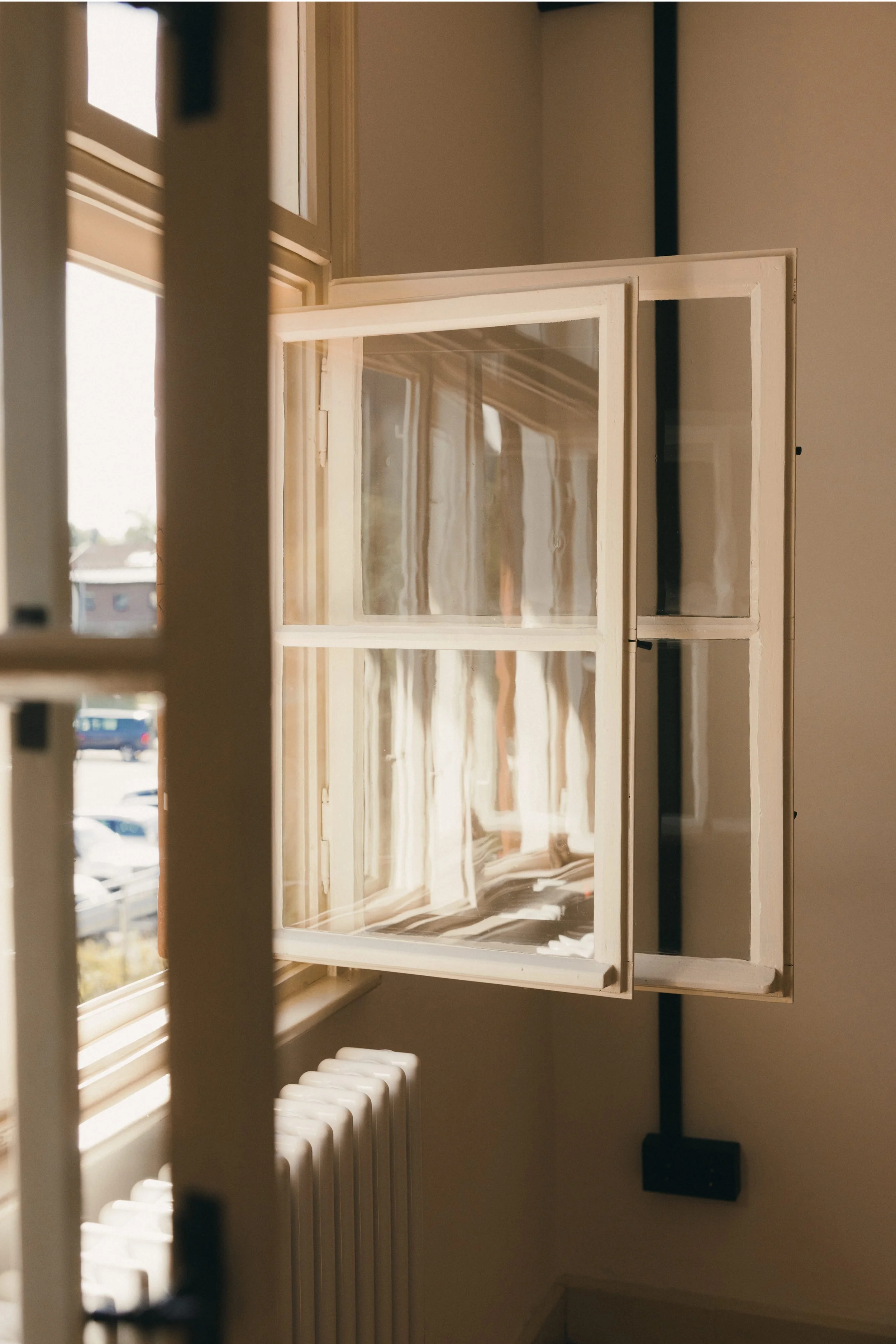 Ein Fenster ist geöffnet und es sind Vorhänge und eine Heiztherme im Raum sichtbar.