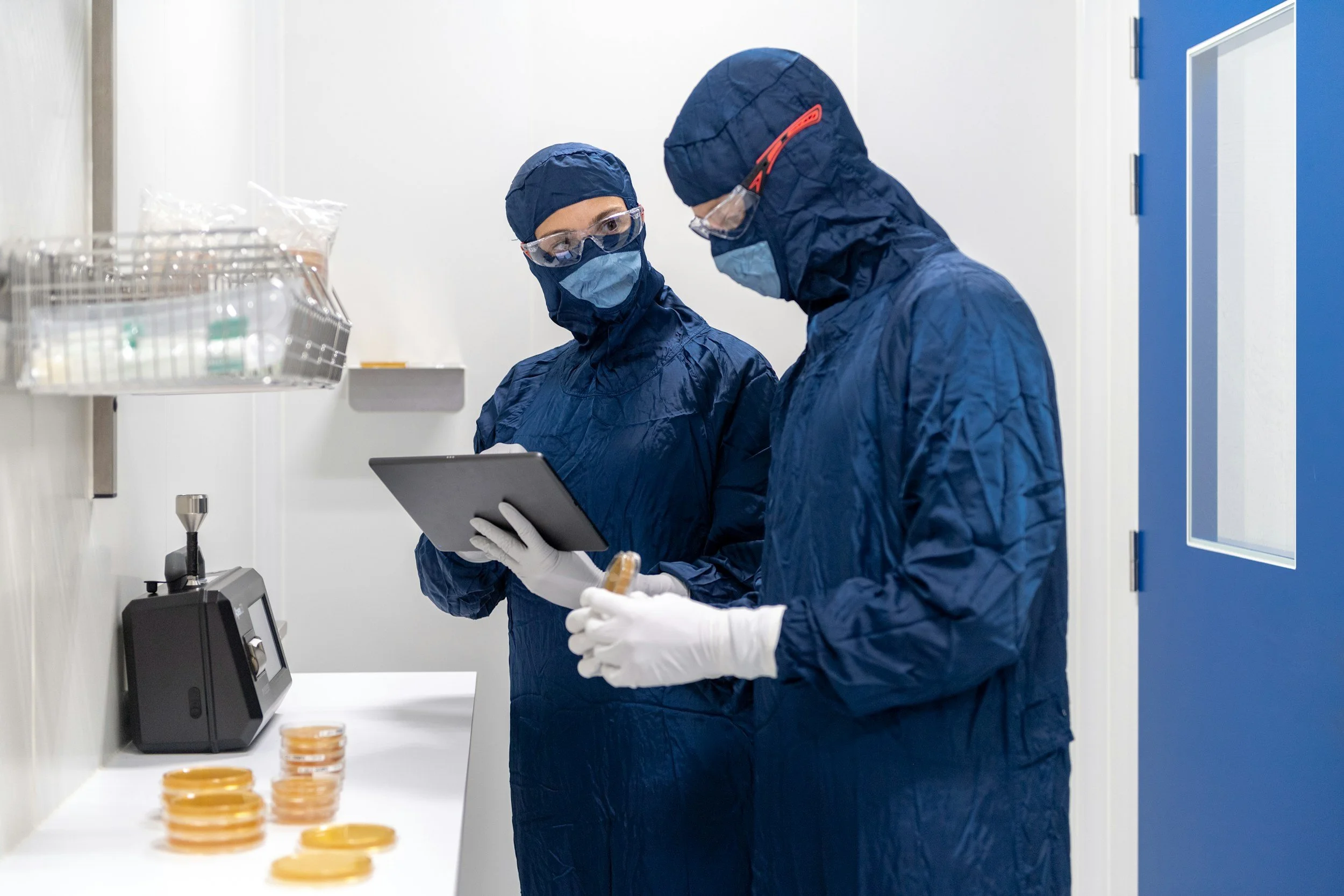 Pharmaceutical manufacturing specialists in cleanroom gowns reviewing production data