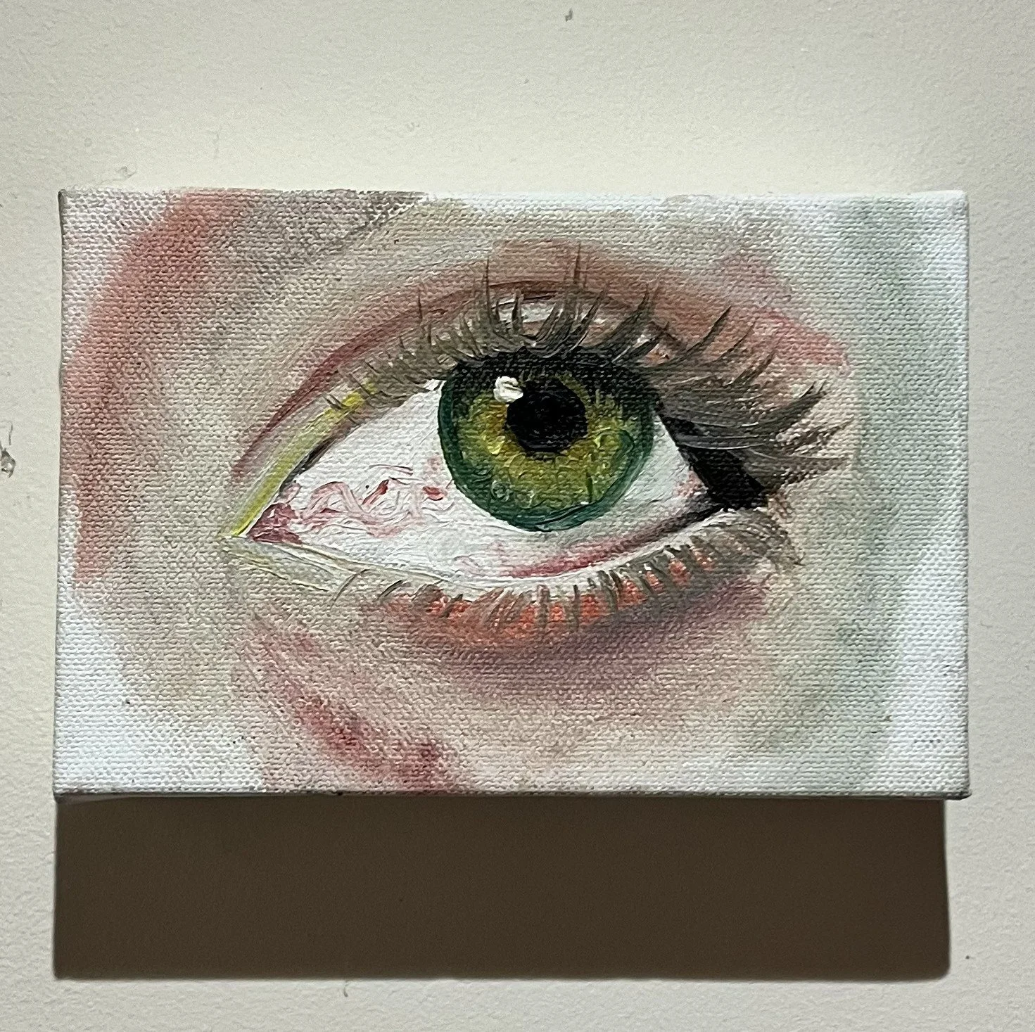 Painting of a realistic human eye with green iris on a small canvas