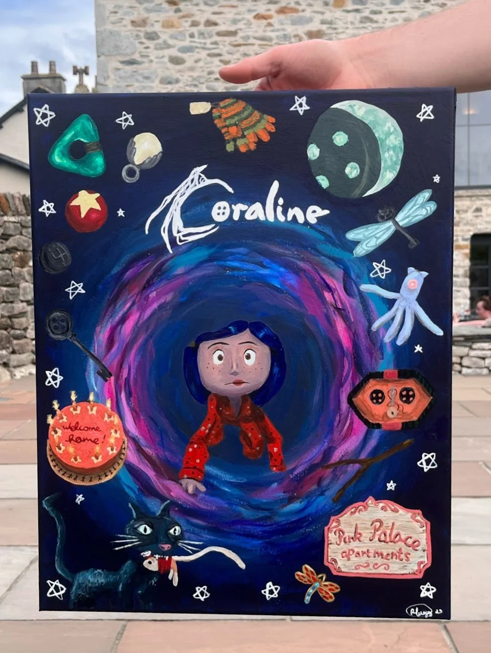 Colorful, whimsical artwork featuring a girl with dark blue hair, surrounded by space-themed objects like planets, stars, a moon, dragonfly, octopus, and a black cat, with the title 'Coraline' in the center.