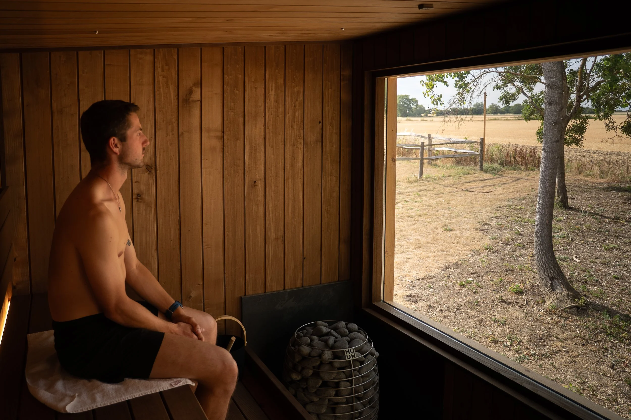 Person enjoying panoramic views across the Essex countryside from The Hide sauna at Houchins, Coggeshall