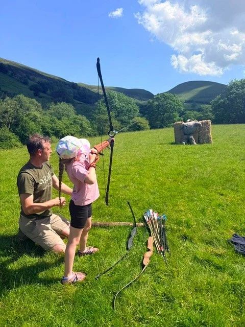 A man and girl practicing archery in a field