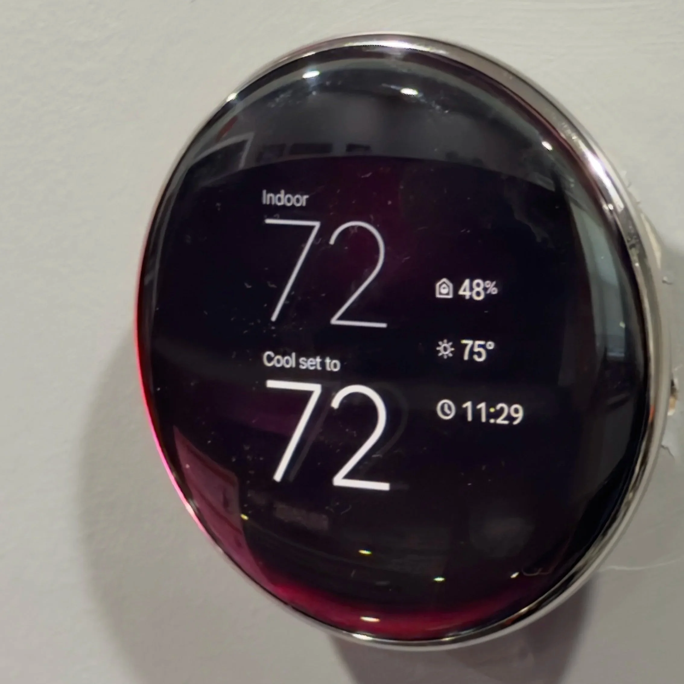 Close-up of a digital thermostat display showing indoor temperature 72°F, 48% humidity, and 75°F outside temperature.