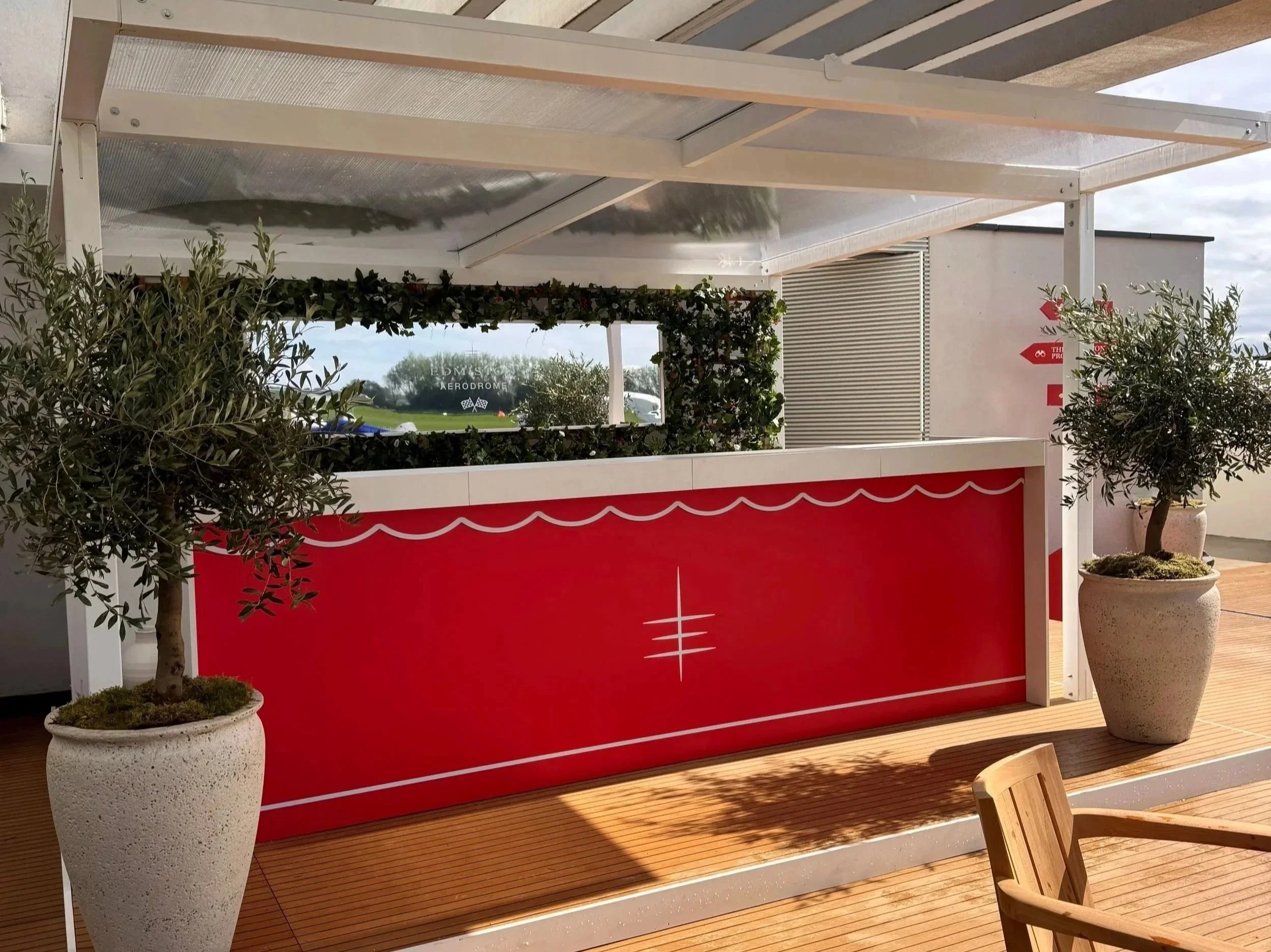 Branded mobile bar hire, 3.6m straight bar counter, white tops, potted olive trees, foliage decorating and branded mirror.jpg