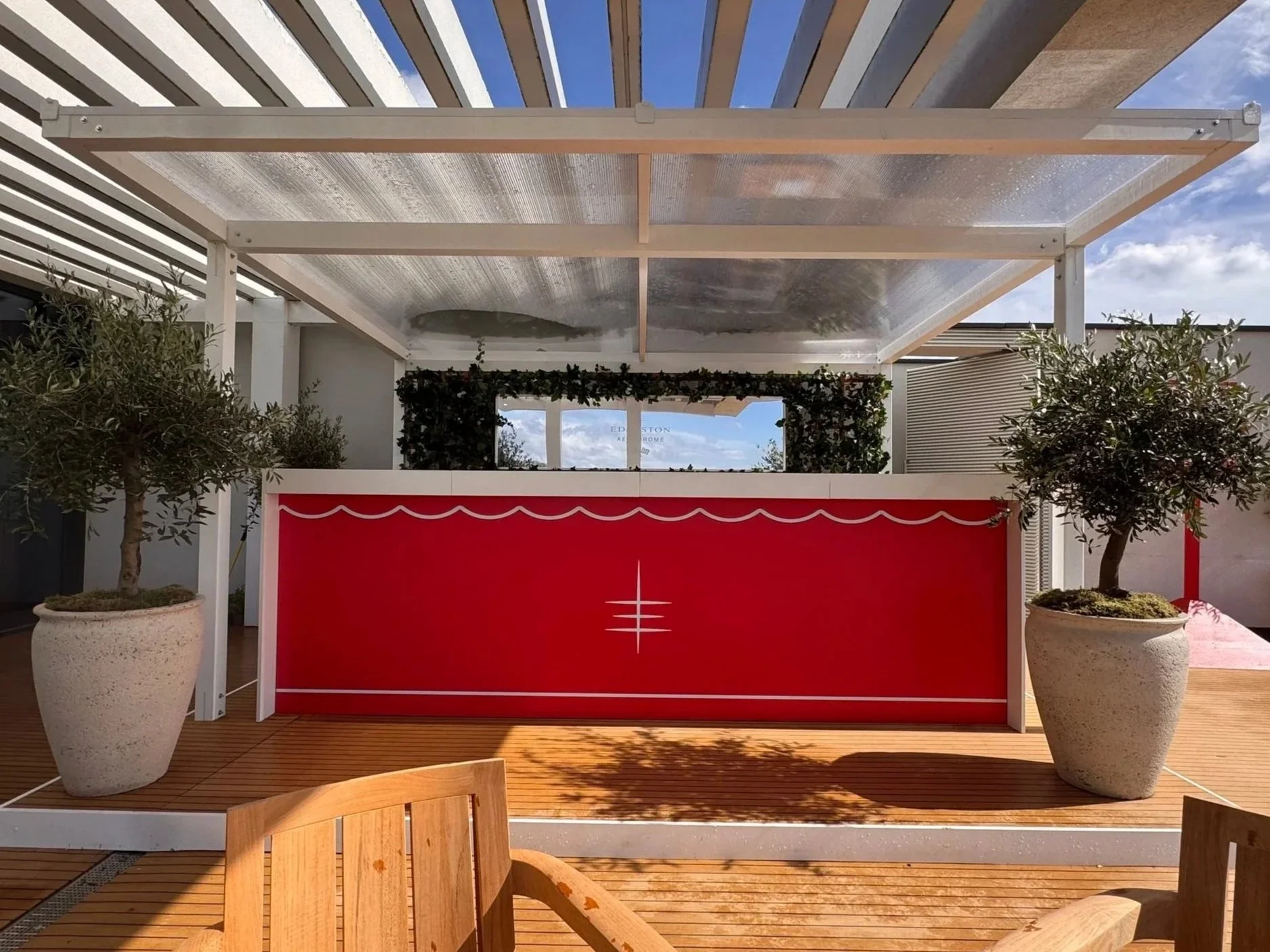 3.6m branded mobile bar with white tops and scenic setting, potted olive trees and faux foliage.jpg