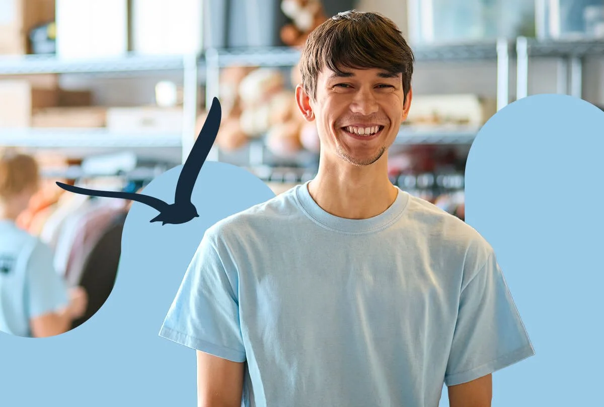 Jeune homme souriant portant un t-shirt bleu clair dans une friperie.