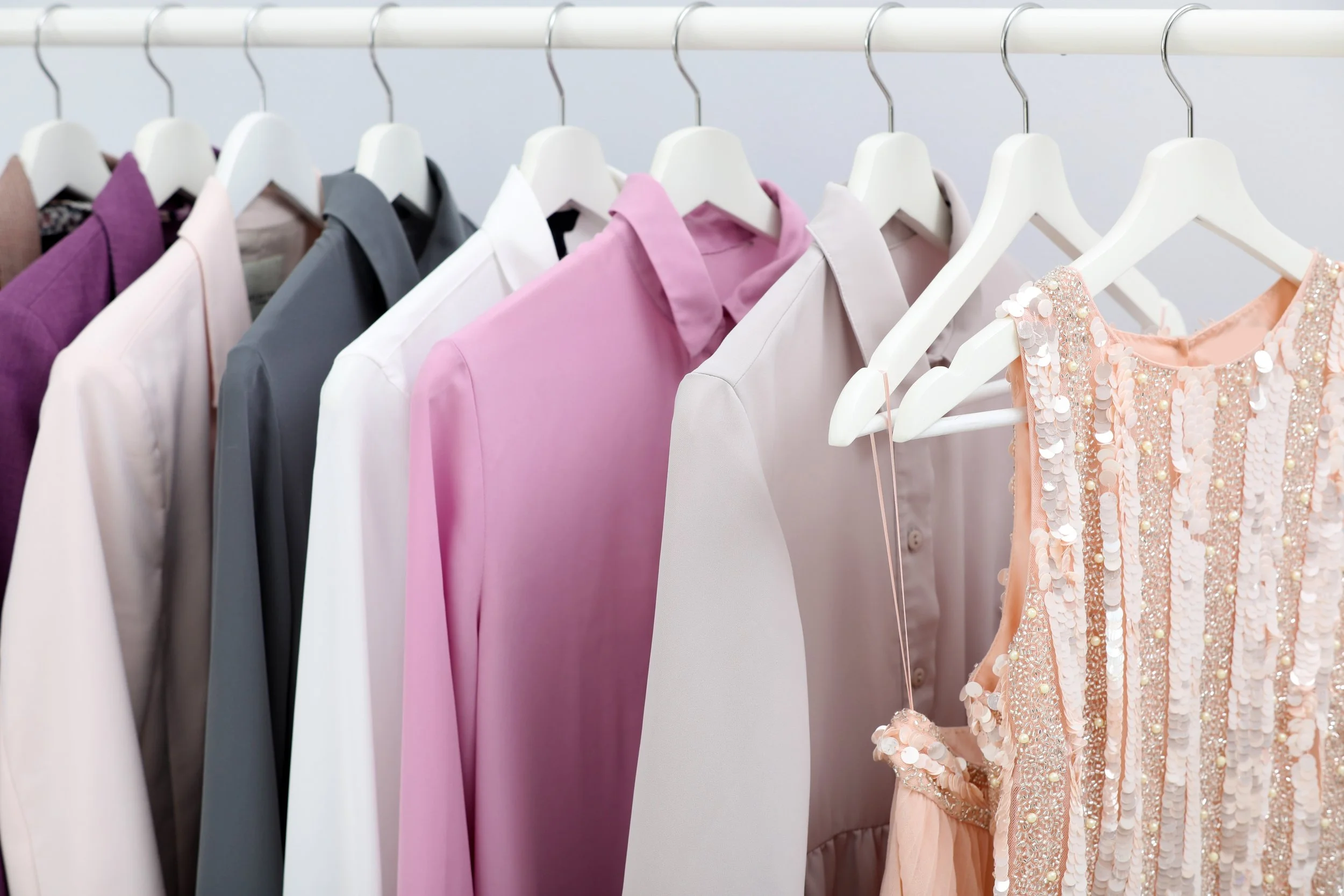 Clothing racks displaying dresses in various colors including lavender, black, pink, white, and a pink dress with sequins. Amazon wishlist