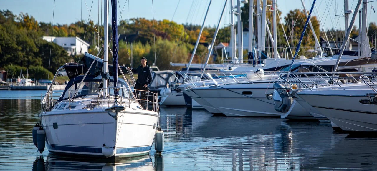 Båter i en marina, med en person som står på en av båtene.
