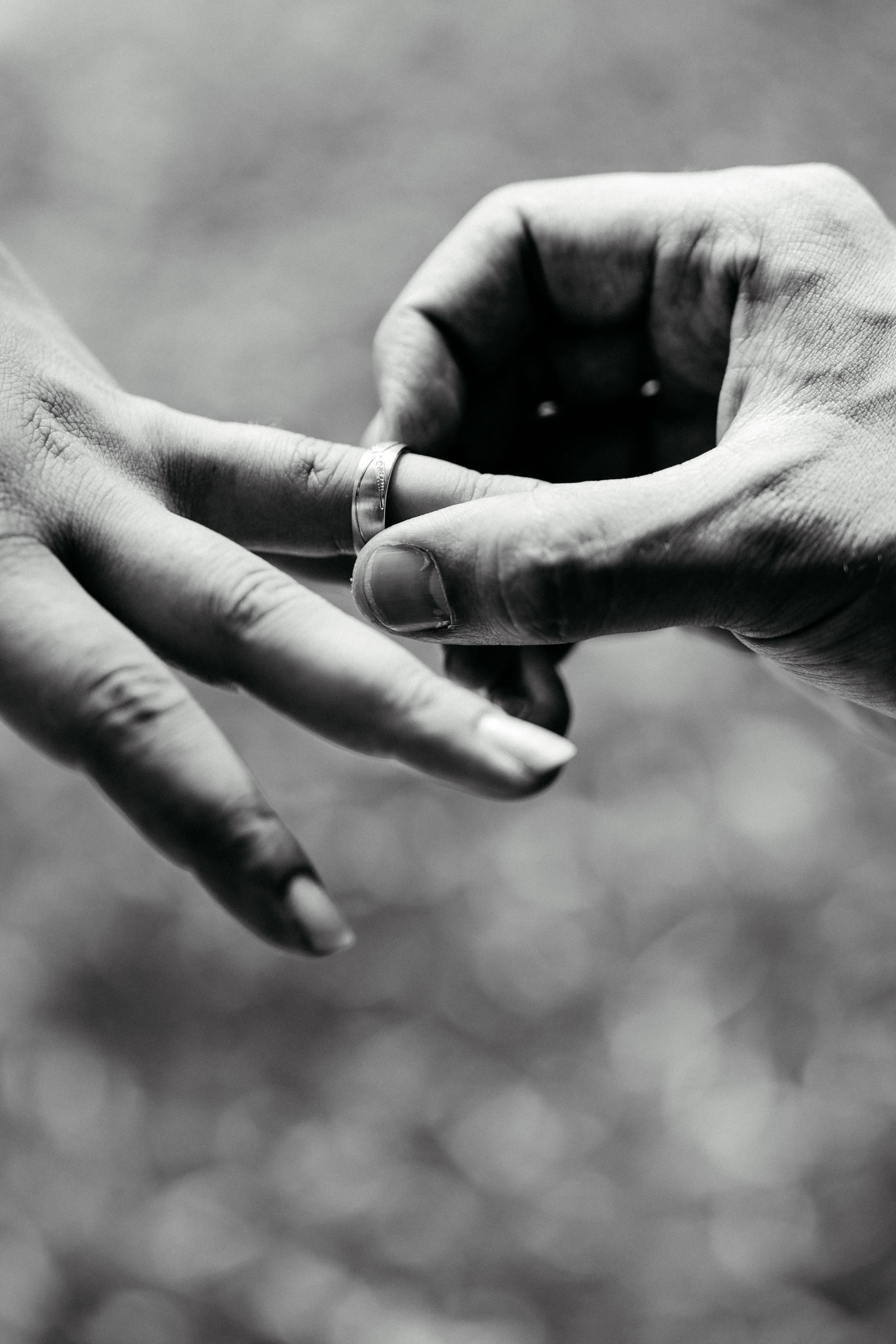 Nahaufnahme zweier Hände, die sich berühren, mit einem Silberring auf dem Finger, in Schwarzweiß aufgenommen.