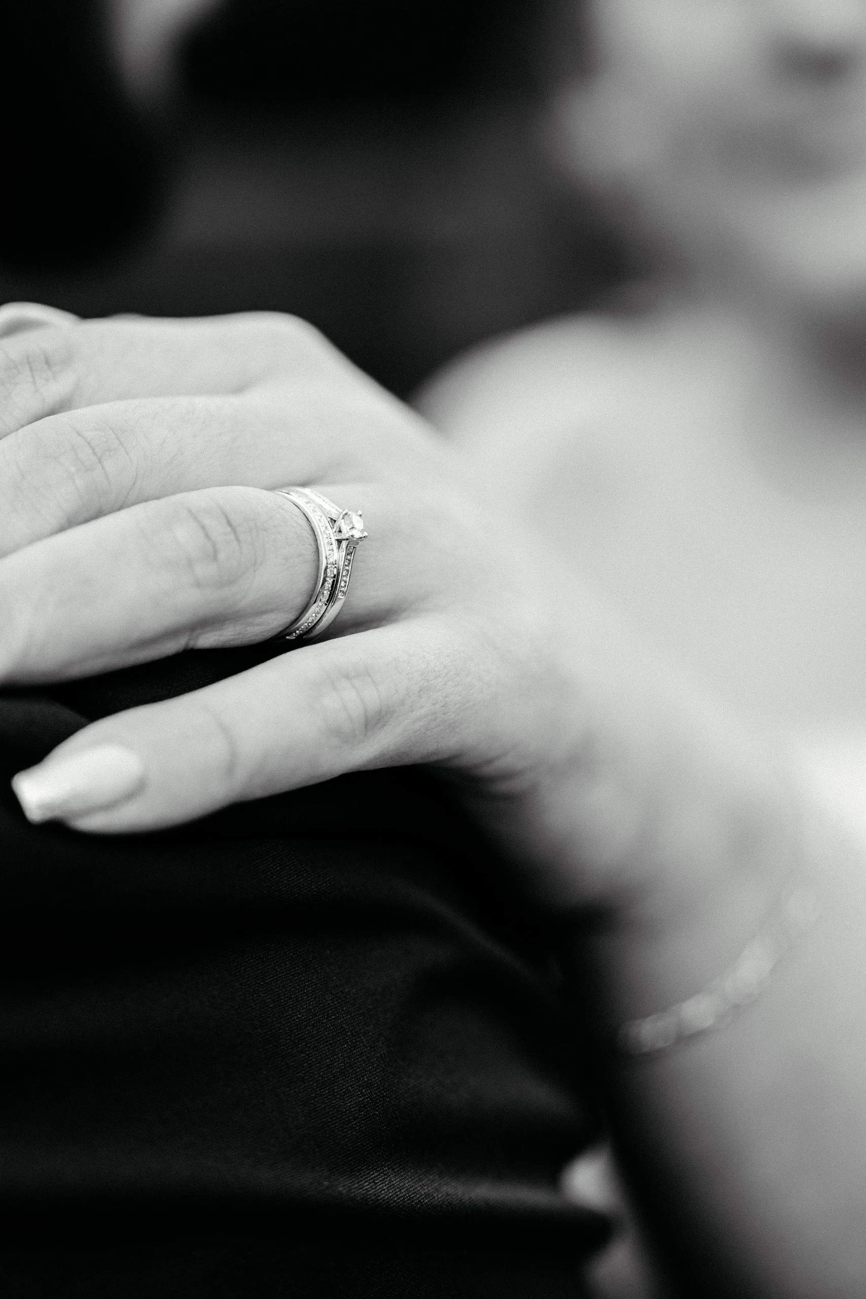 Nahaufnahme eines Handrings mit einem großen Diamanten auf dem Ringfinger. Das Bild ist in Schwarz-Weiß.