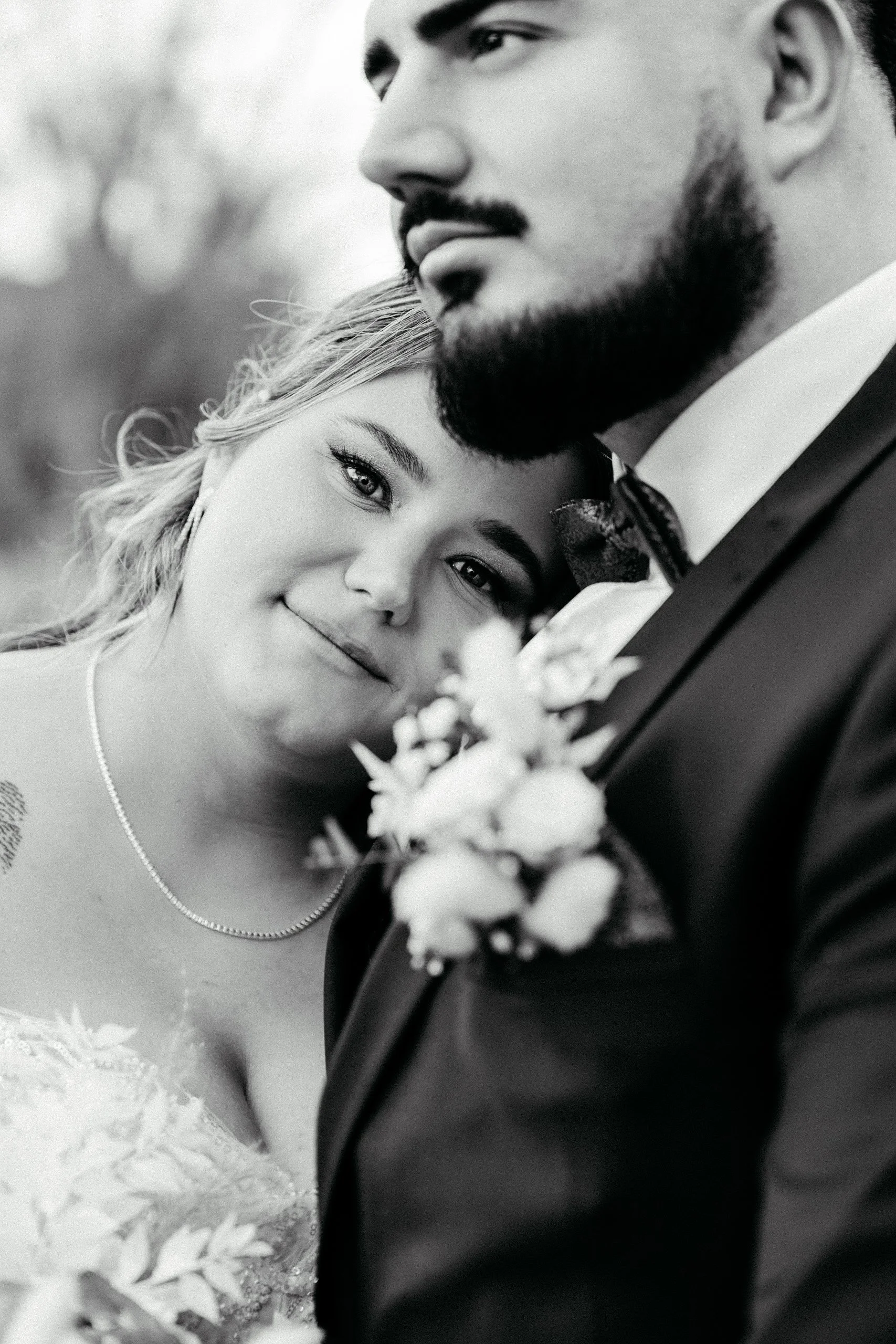Schwarz-Weiß-Foto eines Paares, das sich bei einer besonderen Gelegenheit, vermutlich einer Hochzeit, nahe beieinander umarmt, mit Fokus auf die Gesichter und die intime Stimmung.