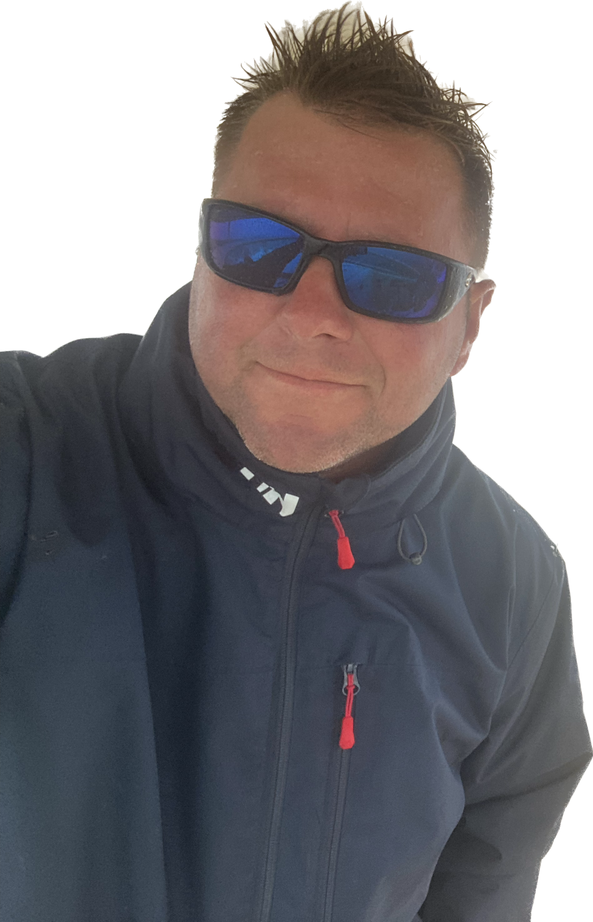 A man with short dark hair wearing reflective sporty sunglasses, a black jacket with red accents, and a high collar, smiling slightly.