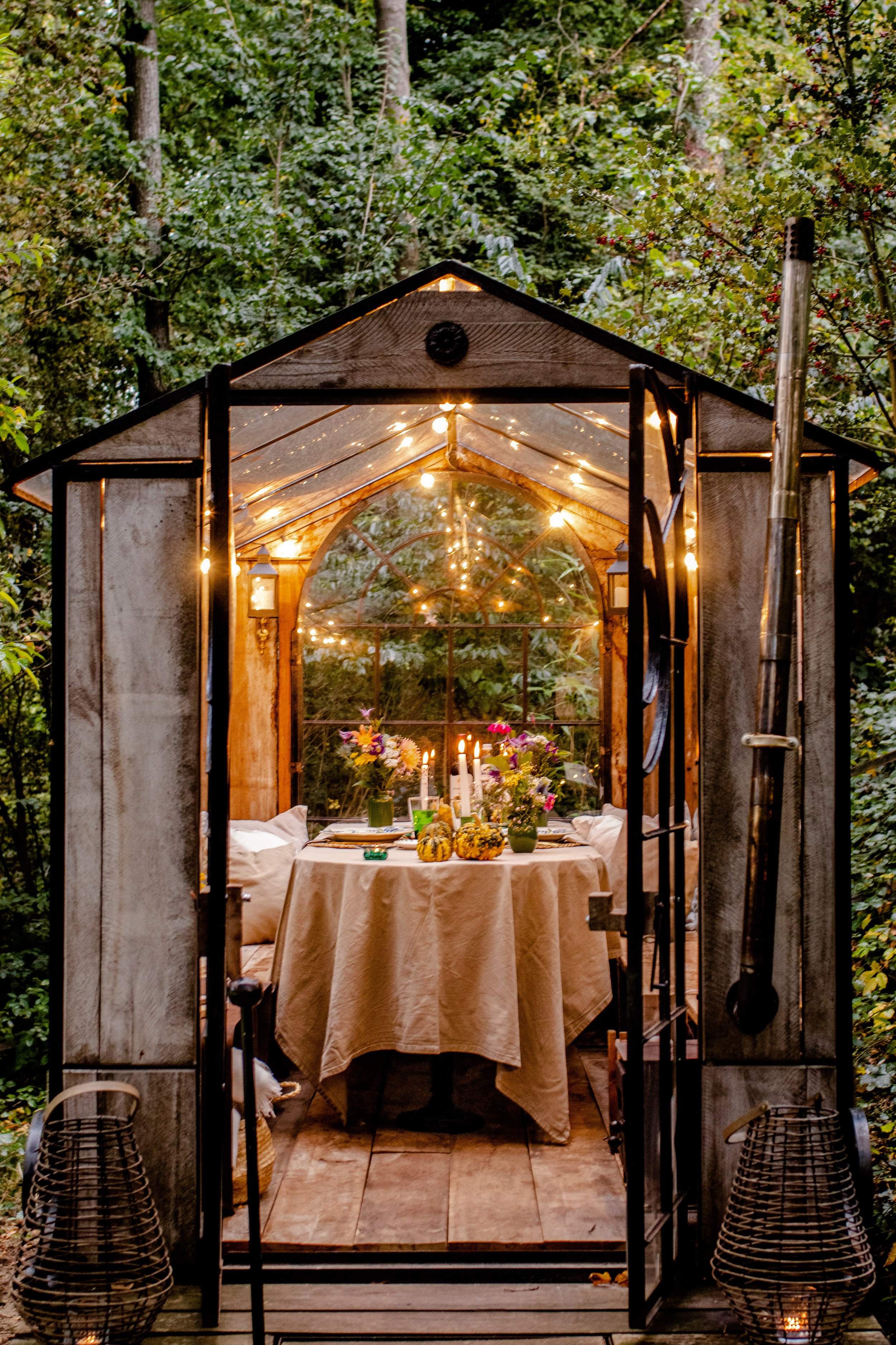 Candlelit table set for a private dinner inside La Roulotte, a glass cabin in the forest.